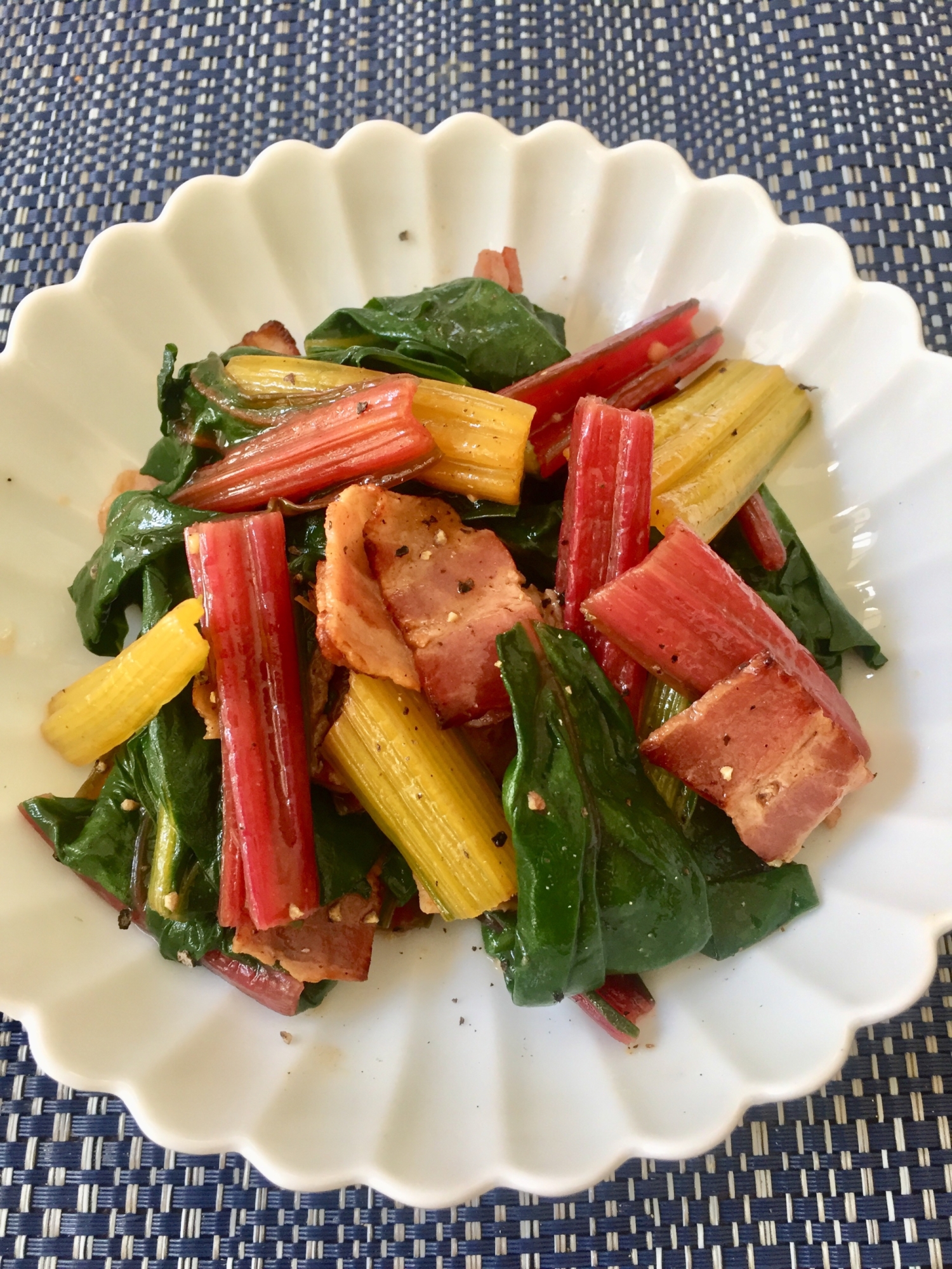 白い皿に盛られたスイスチャードとベーコンのにんにく炒め