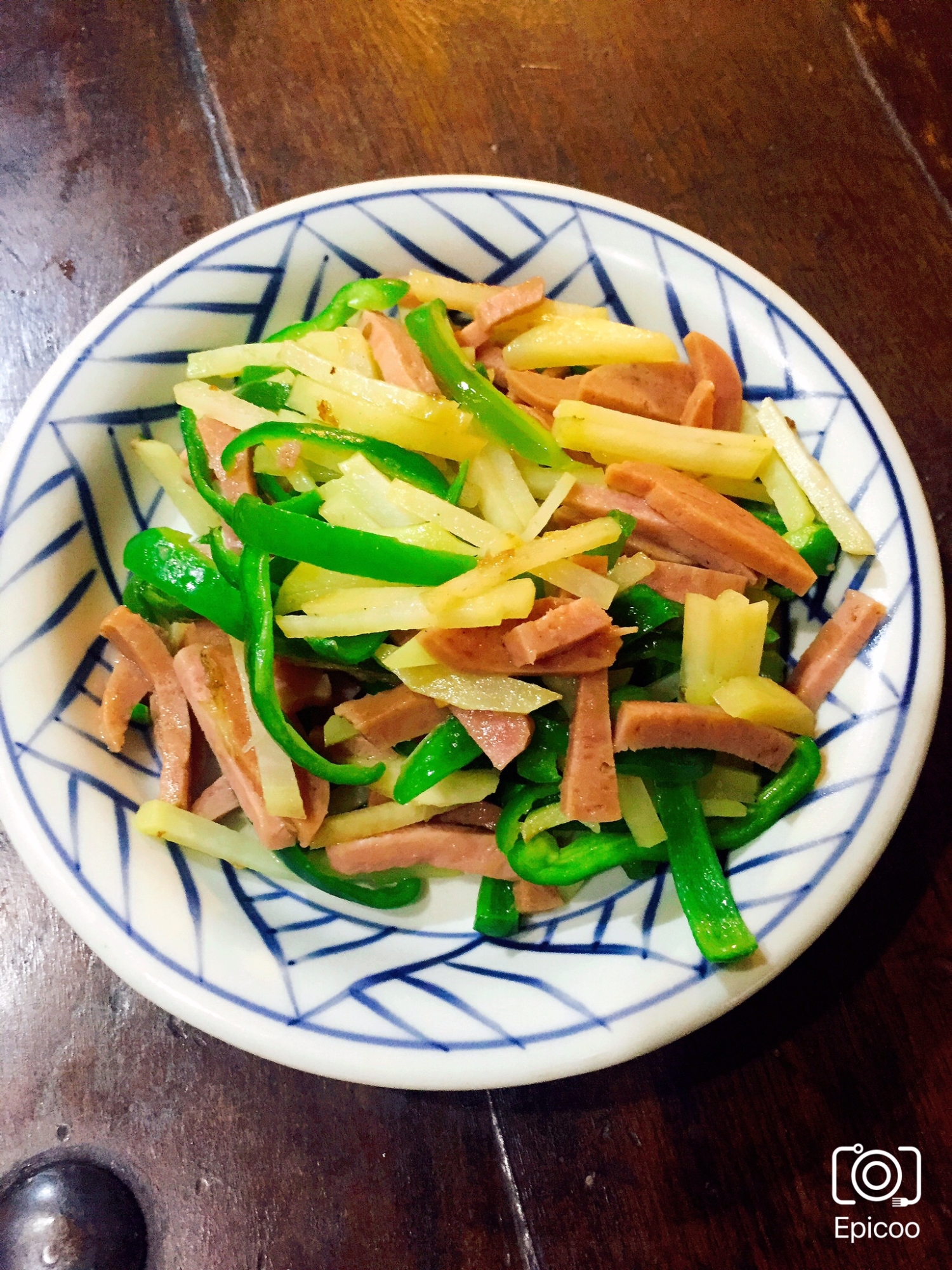 白地に青い模様入りの皿に盛られたスパムとじゃがいもとピーマンの炒め物