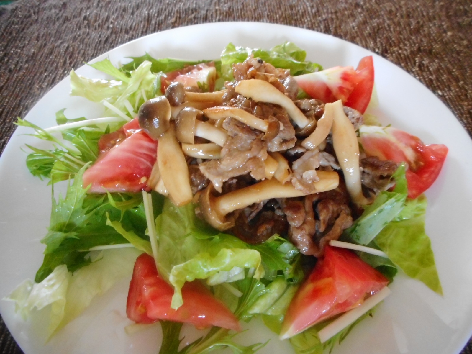 白い皿に盛り付けたラム肉としめじのサラダ