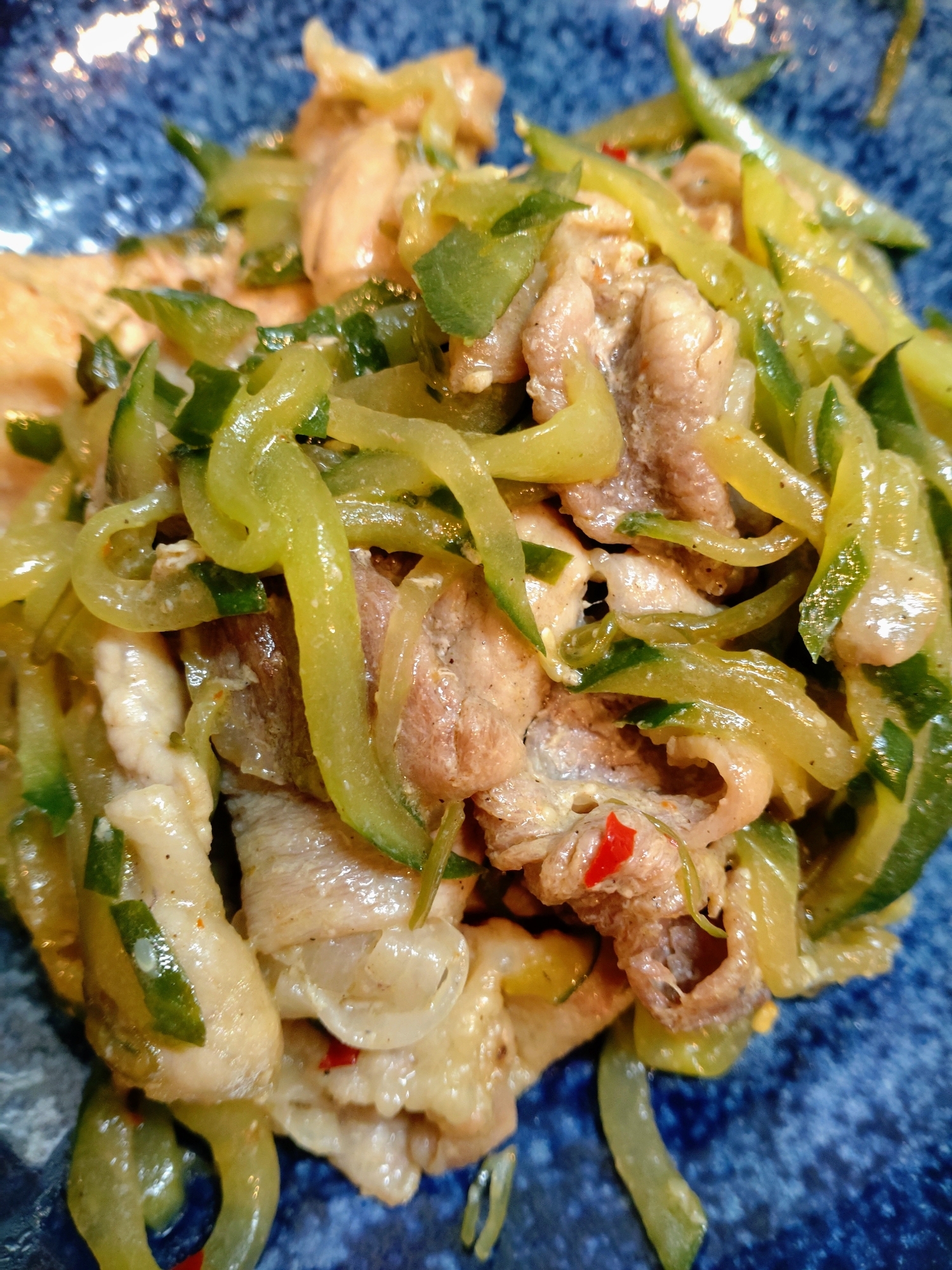 青い皿に盛られためかぶと豚肉のきんぴら炒め