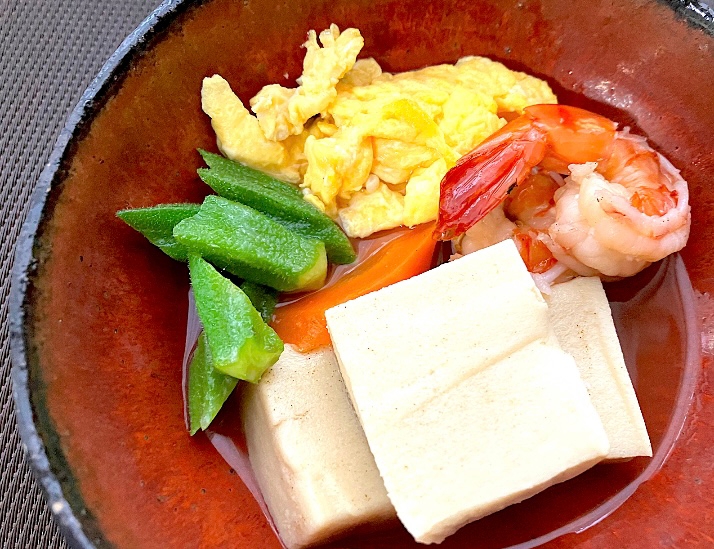 赤い器に盛り付けられた高野豆腐と野菜の炊き合わせ