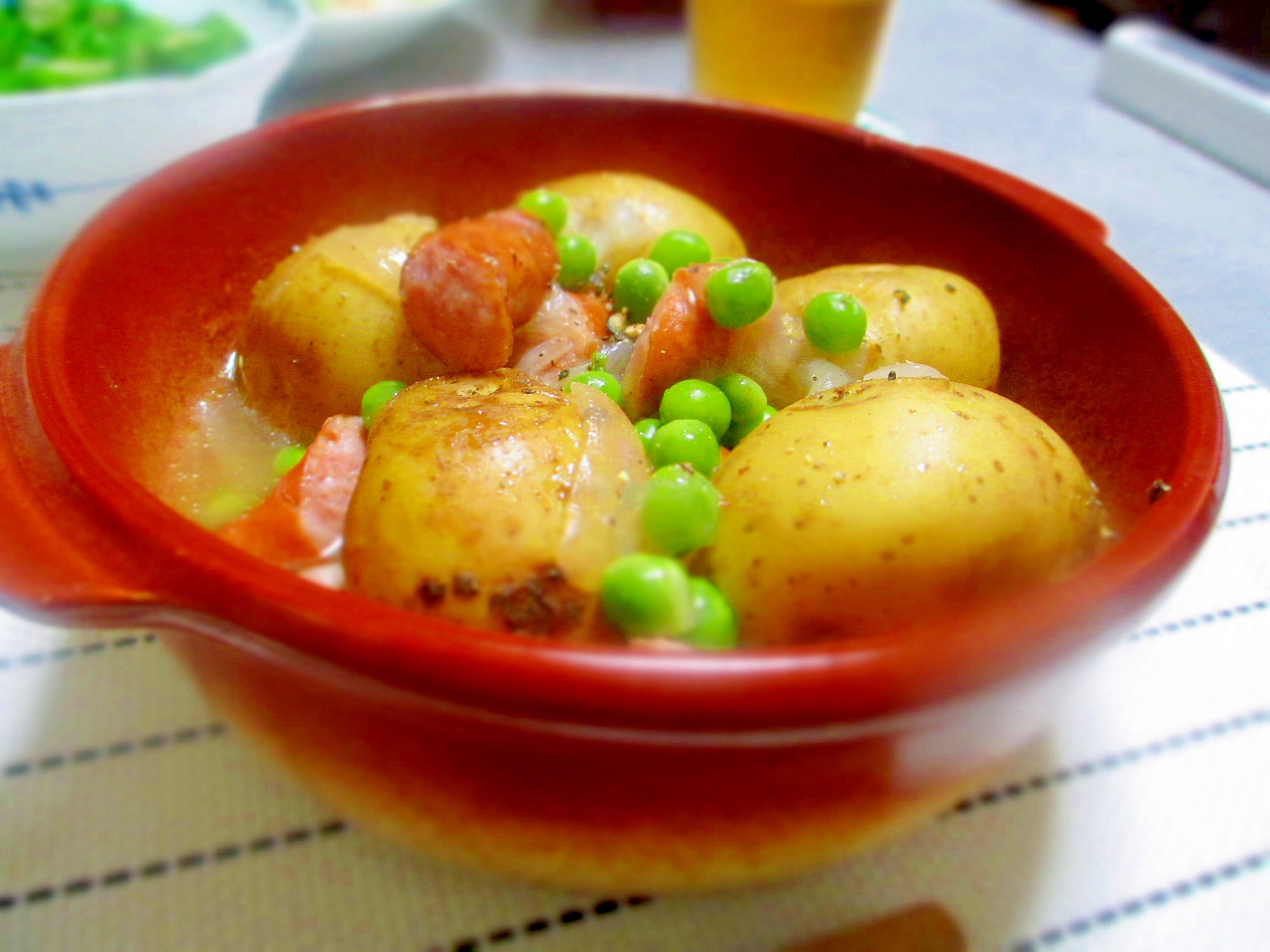 赤い器に盛り付けられたえんどう豆とじゃがいものコンソメ煮