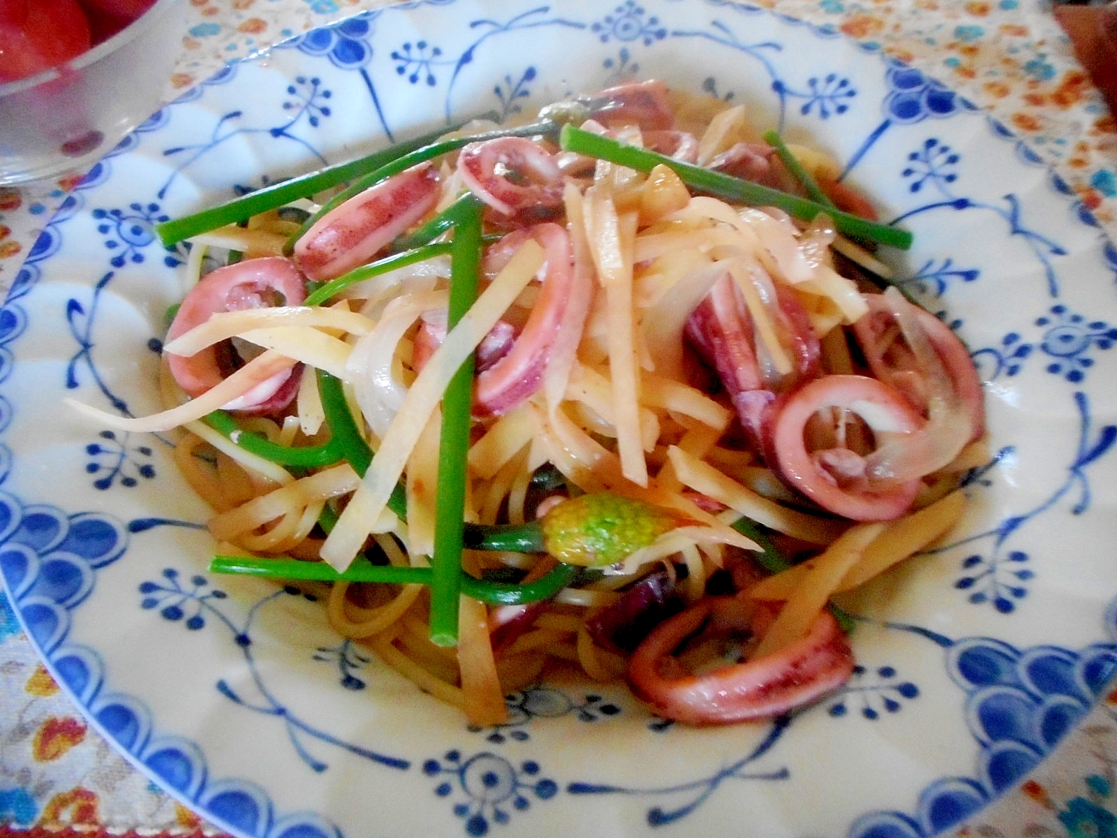青い絵柄の皿に入った行者ニンニクのつぼみとイカのパスタ