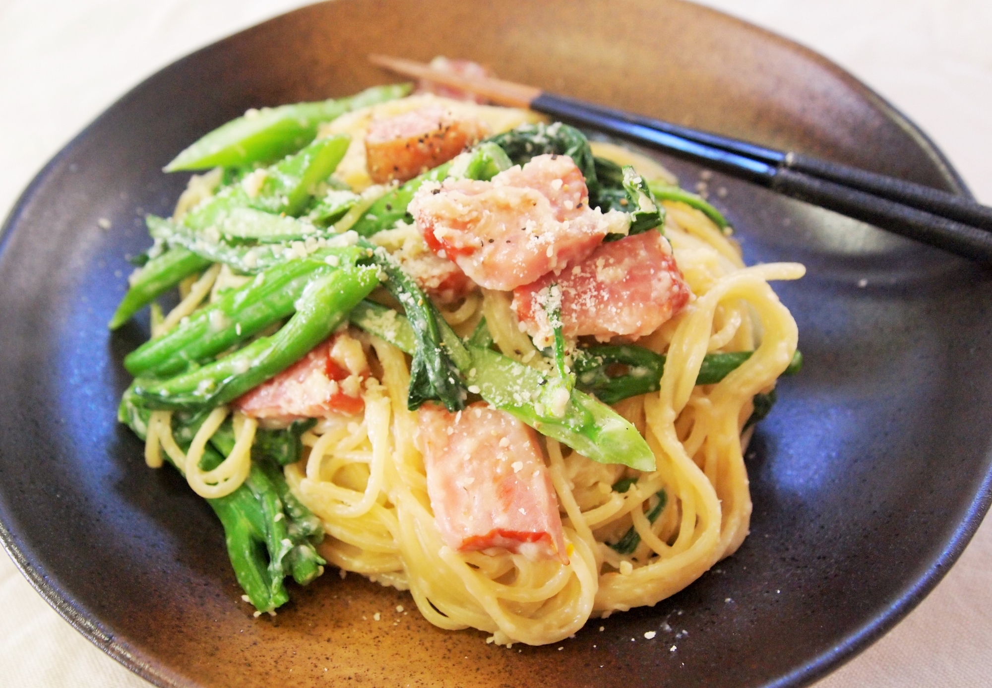 黒いお皿に盛り付けられたベーコンとアスパラ菜のクリームパスタ