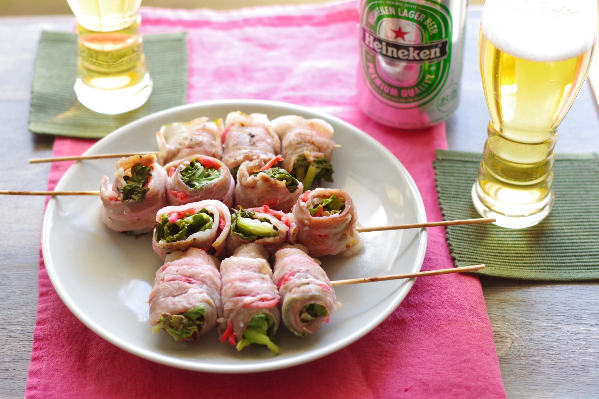 皿に盛りつけられた肉巻き串とビールの入ったグラス