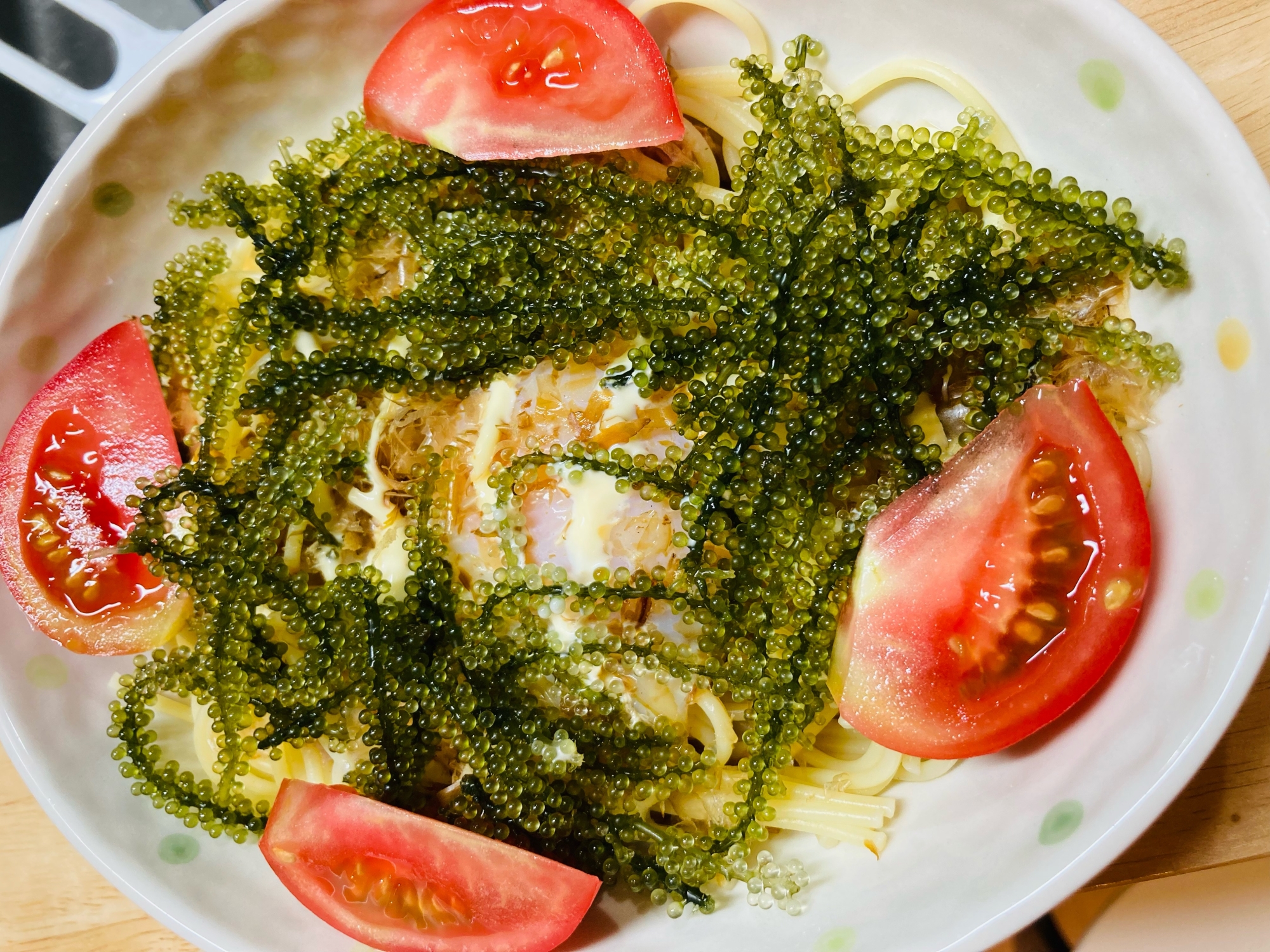 白いお皿に盛り付けられたトマト、海ぶどうパスタ