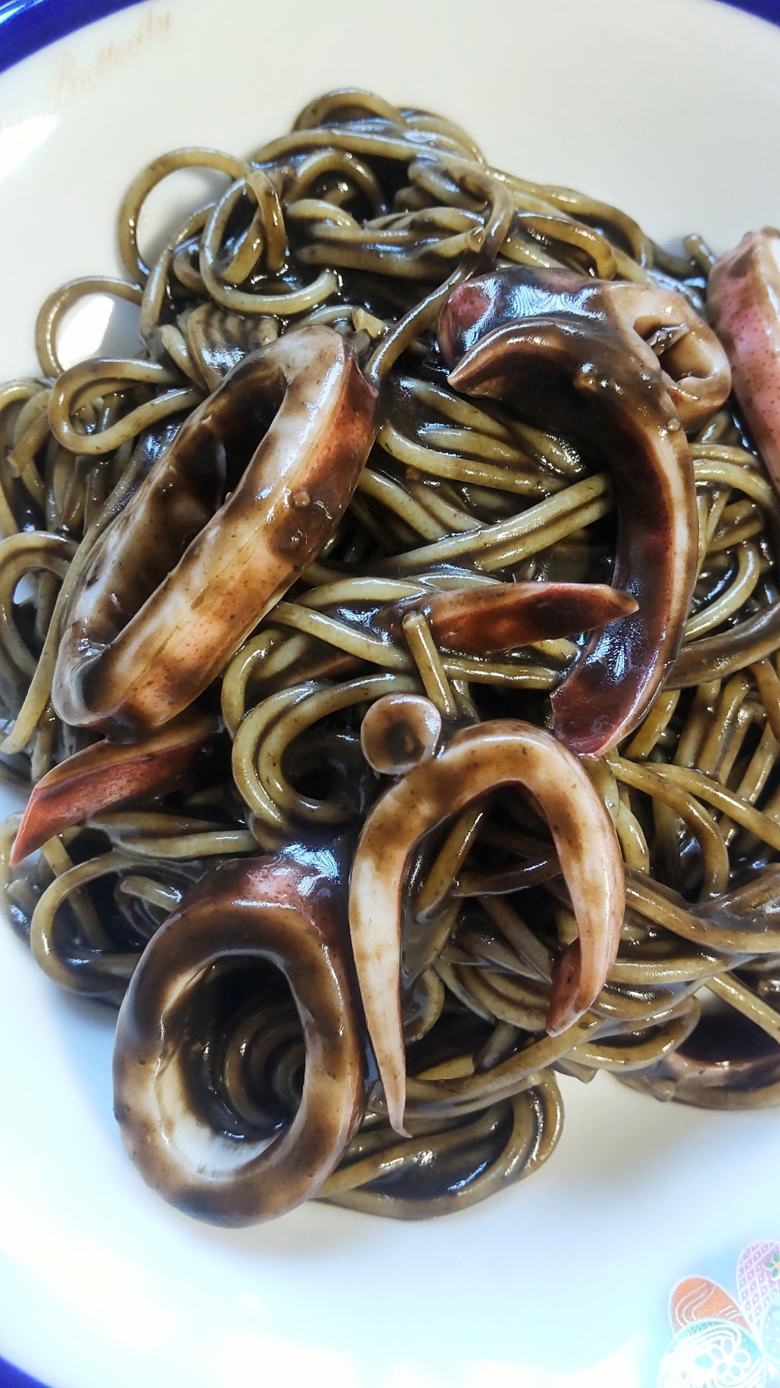 白い皿に盛りつけられたボイルイカのイカスミパスタ