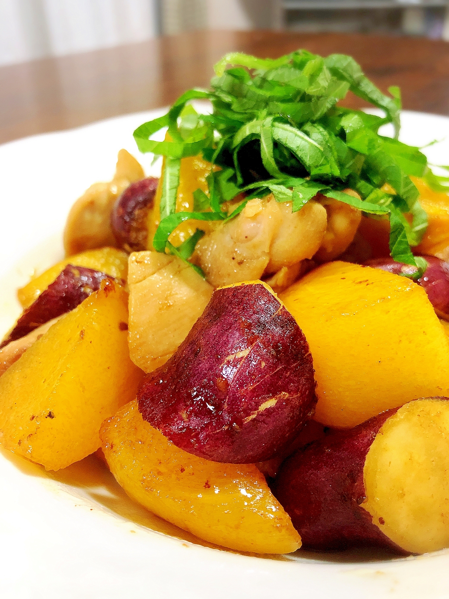 白色の皿に盛られた鶏肉と柿とさつまいものめんつゆバター炒め