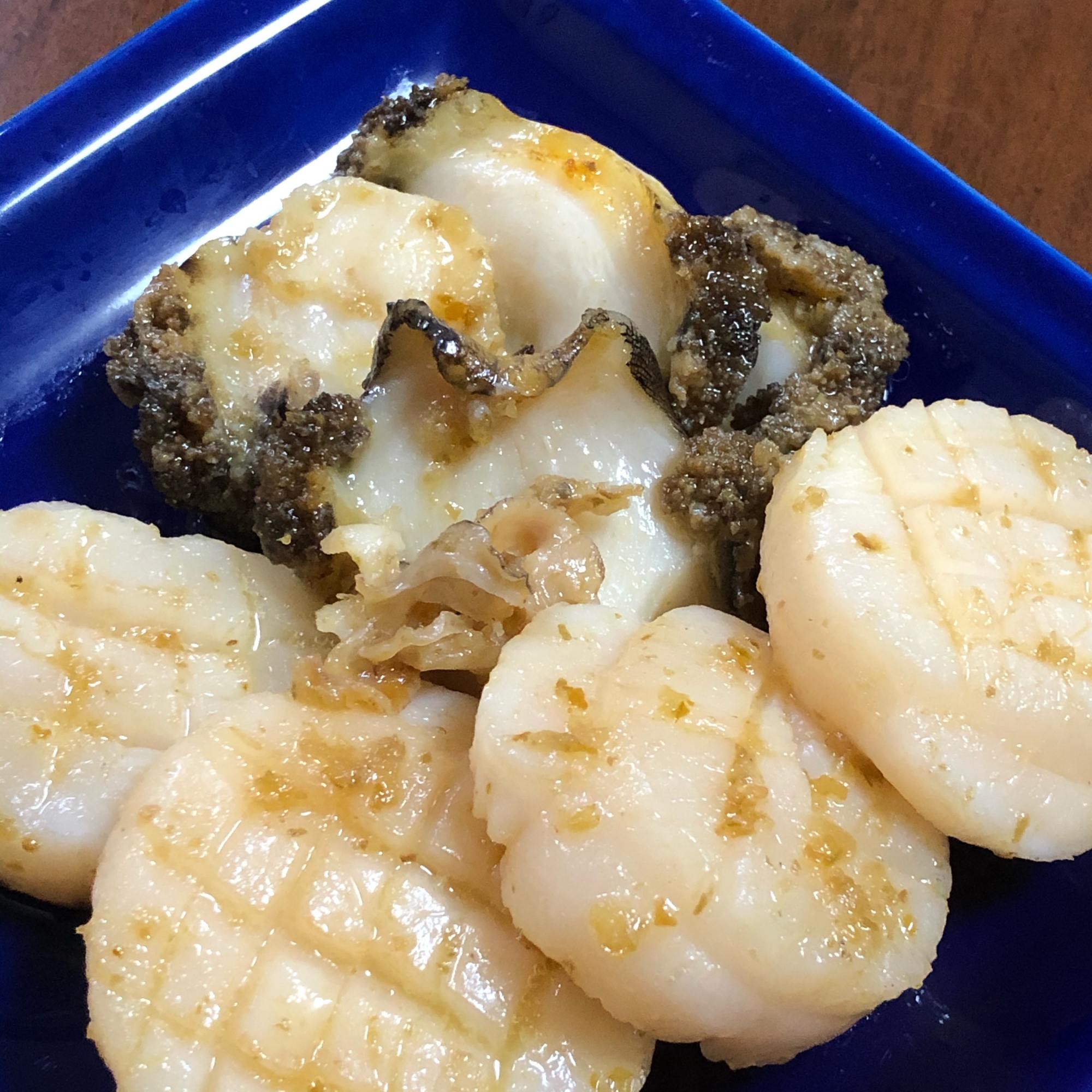青い器にあわびとホタテの柚子こしょうバター焼きが盛られている