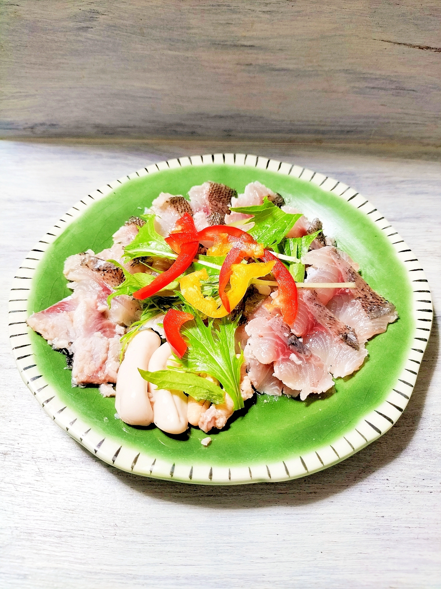 緑の皿に盛られたイサキのカルパッチョ