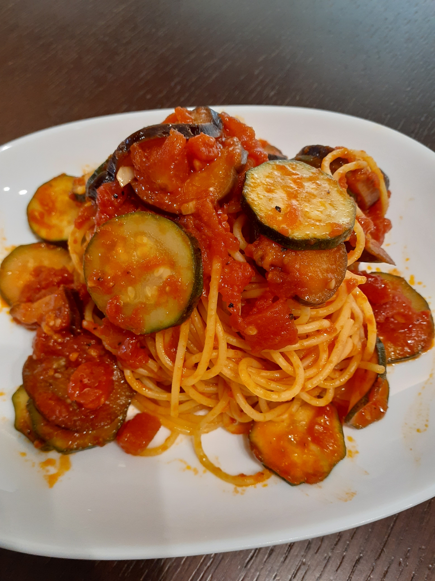 白いプレートに盛り付けたナスとズッキーニのトマトパスタ