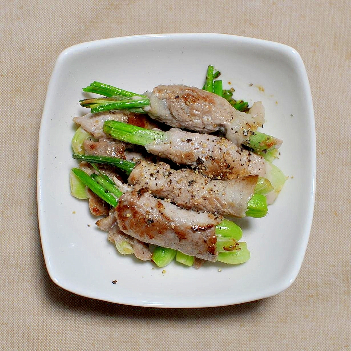 白いお皿に盛り付けられた島らっきょうの肉巻き焼き