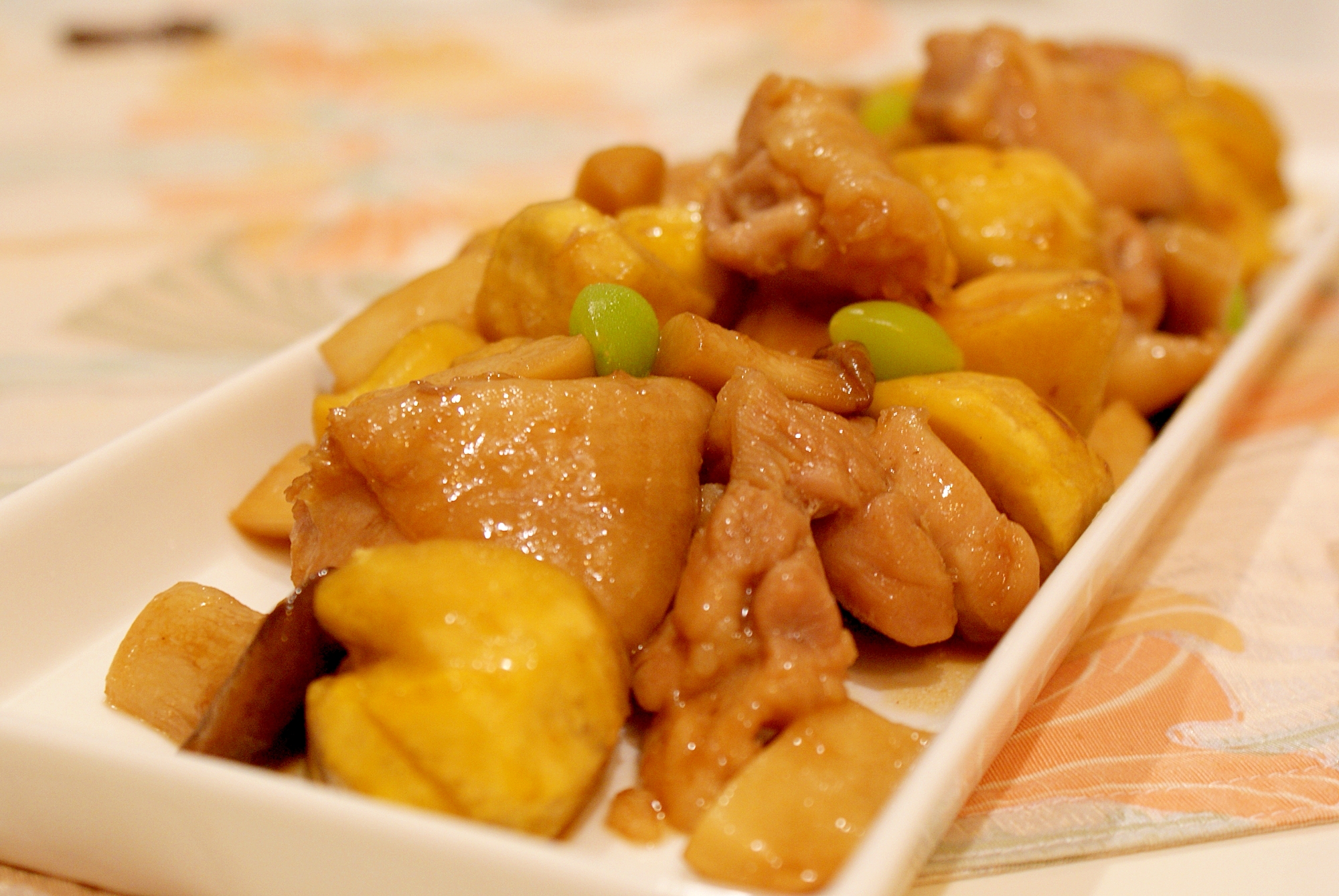 白色の四角の皿に盛られた鶏もも肉、栗、ぎんなんの照り炒め