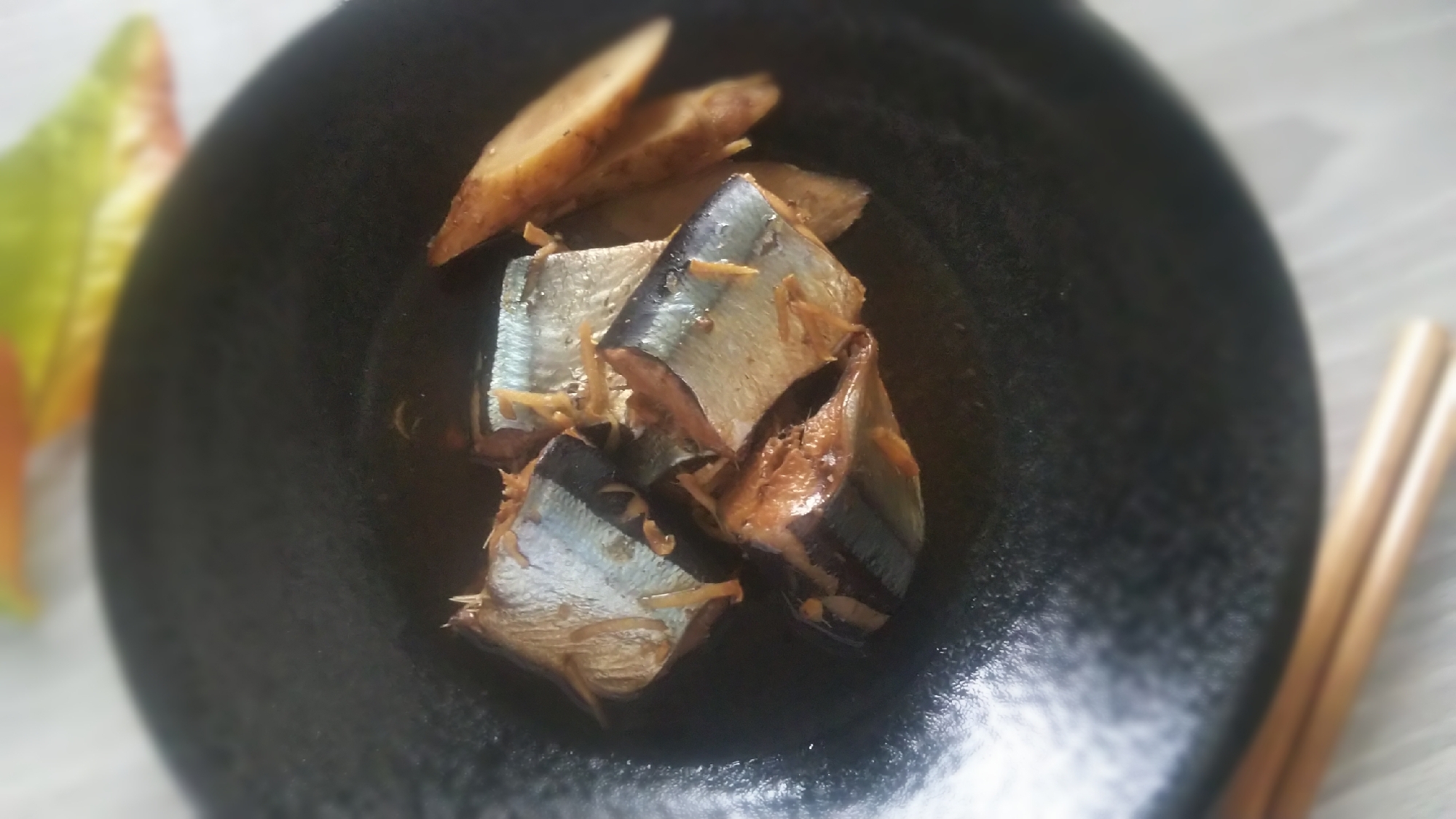 黒い皿に盛られた、さんまのつや煮