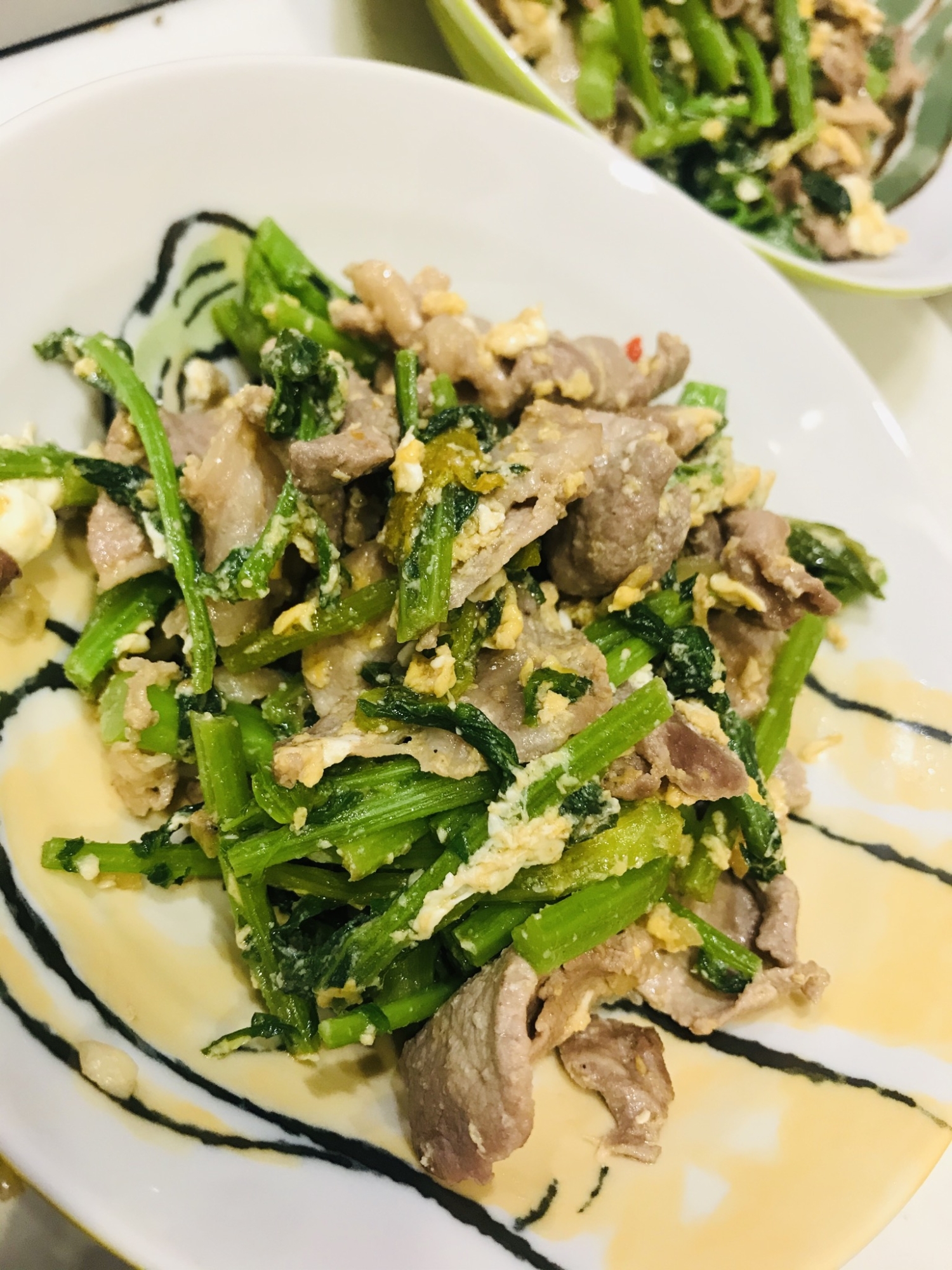 白い皿に盛りつけられたからし菜と豚肉のタイ風ピリ辛炒め