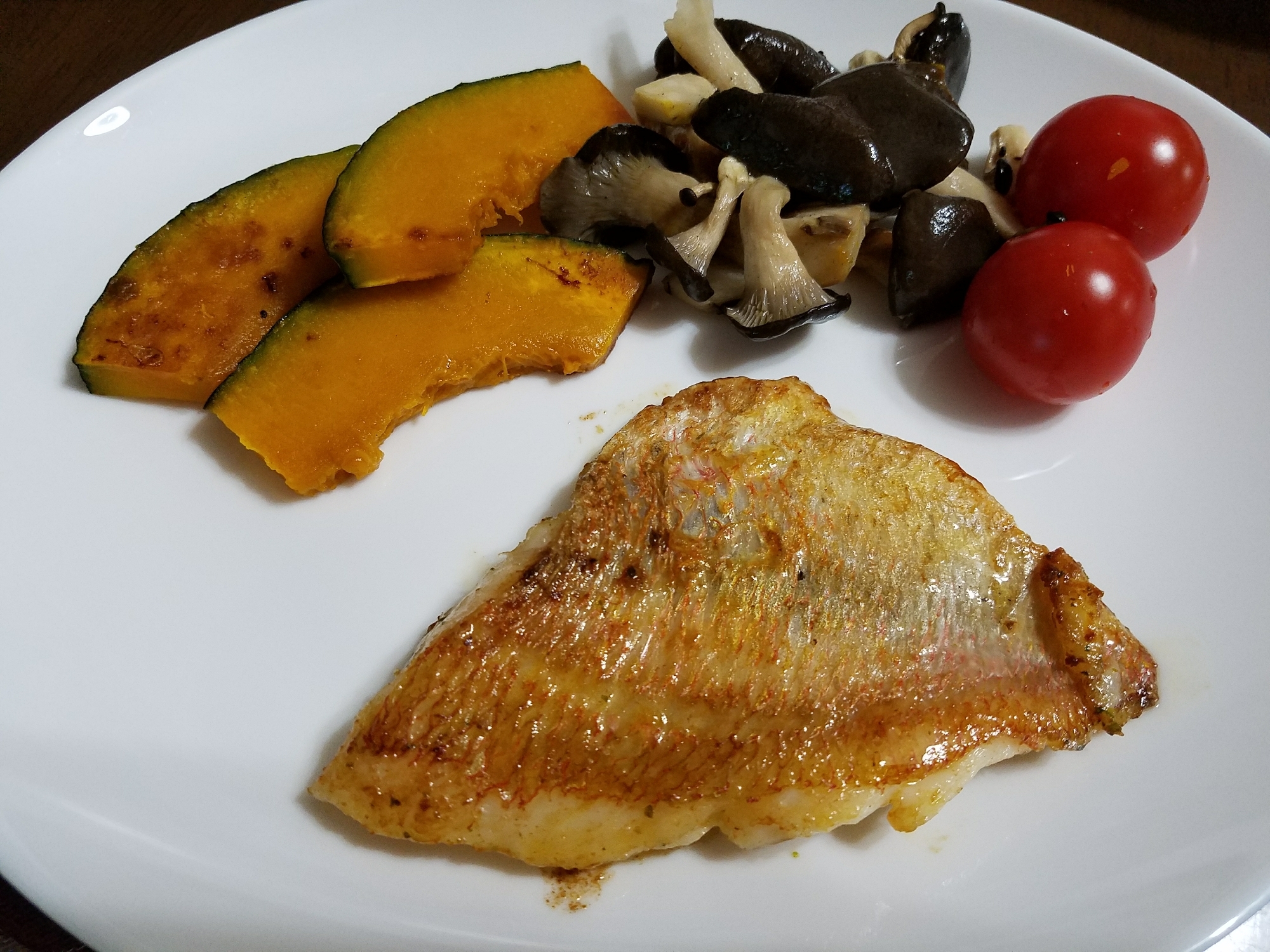 白いお皿に盛り付けられた連子鯛のソテー、かぼちゃ、ひらたけ、トマト