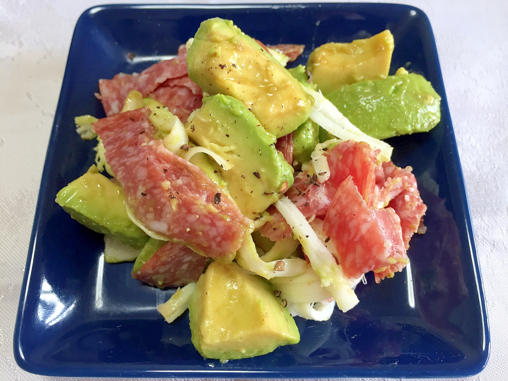 青いお皿に盛り付けられたアボカドとサラミのサラダ