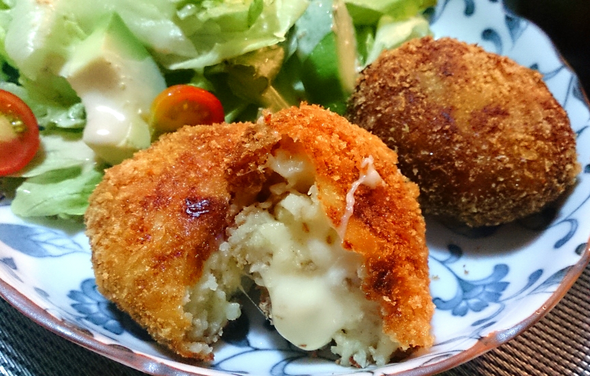 皿に盛り半分に切った、チーズがとろけるコロッケ