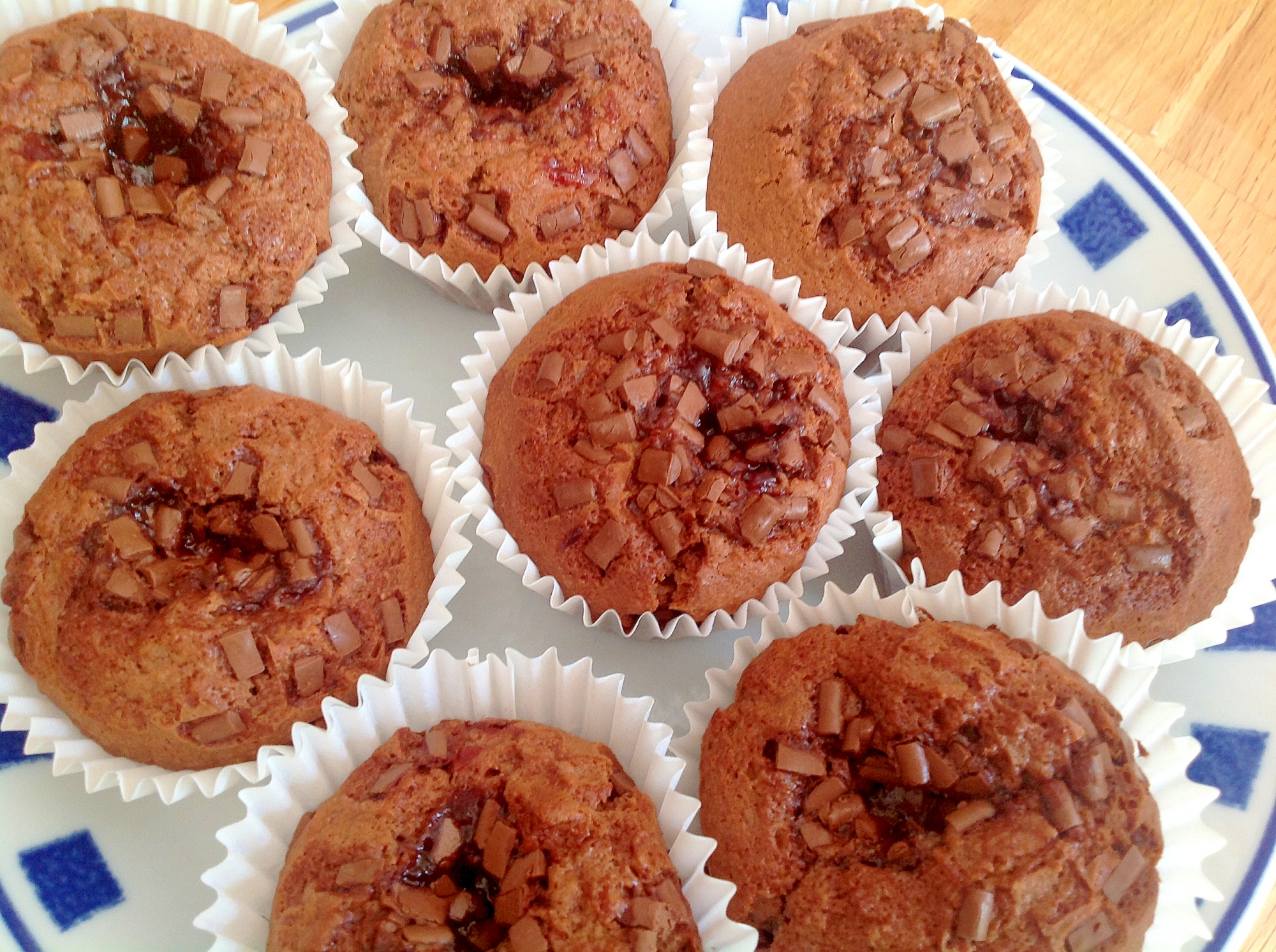 青い四角柄が入った白い皿に盛り付けられたプラムのマフィン