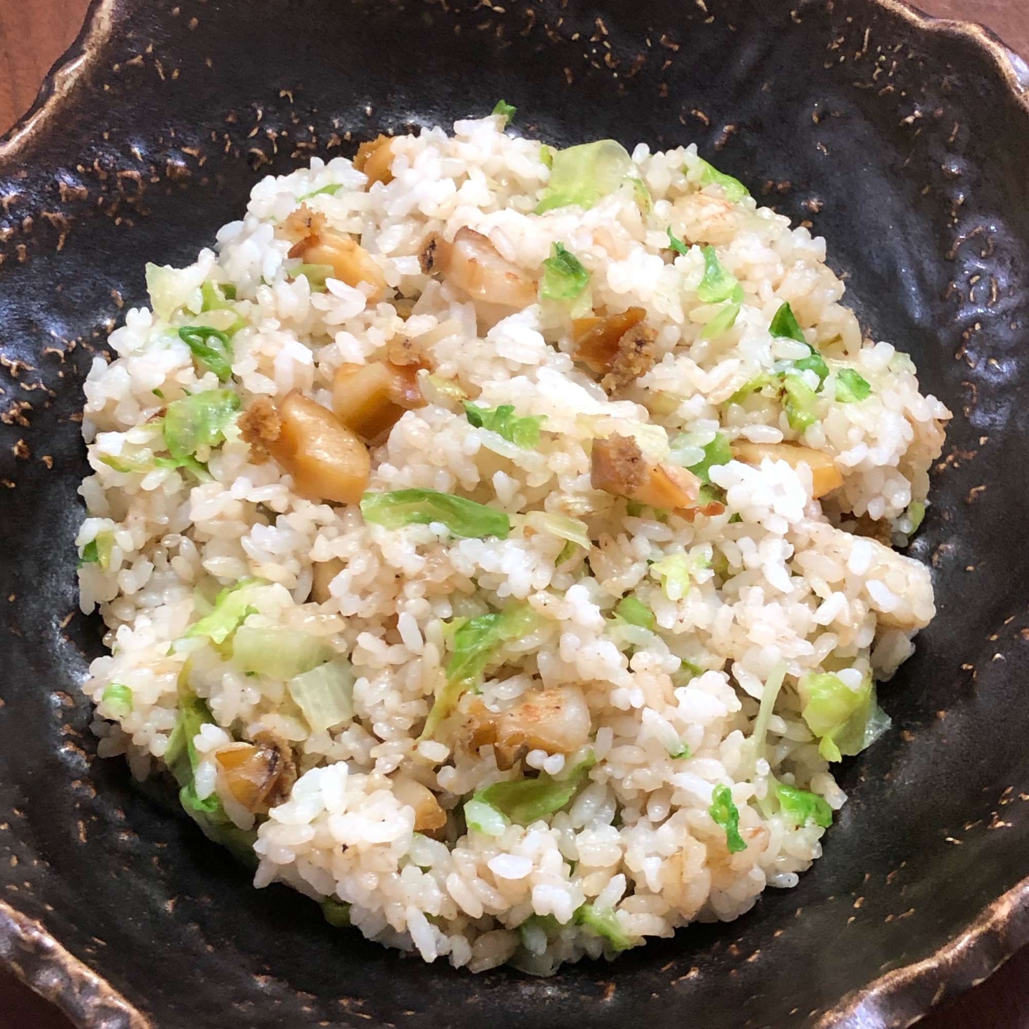 黒の皿にアワビチャーハンがのっている様子