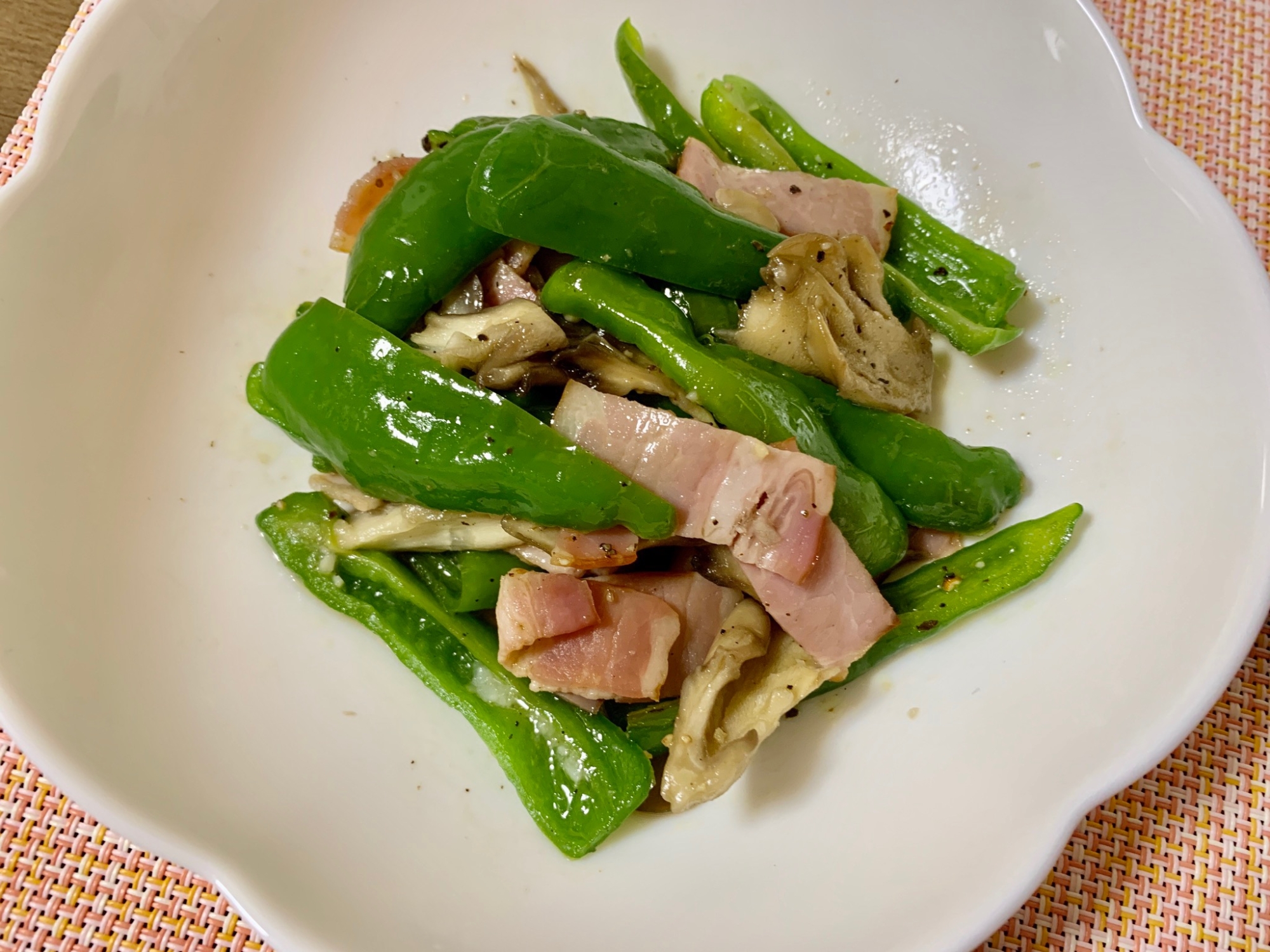 白い皿に入ったジャンボししとうとベーコンのオリーブオイル炒め