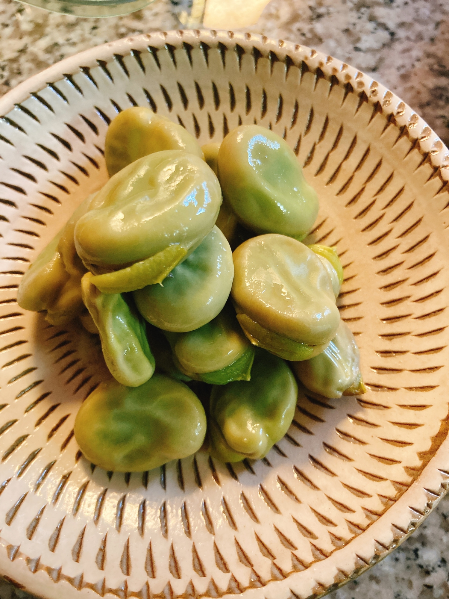 模様の入った灰色の皿に盛られたそら豆の蒸し煮