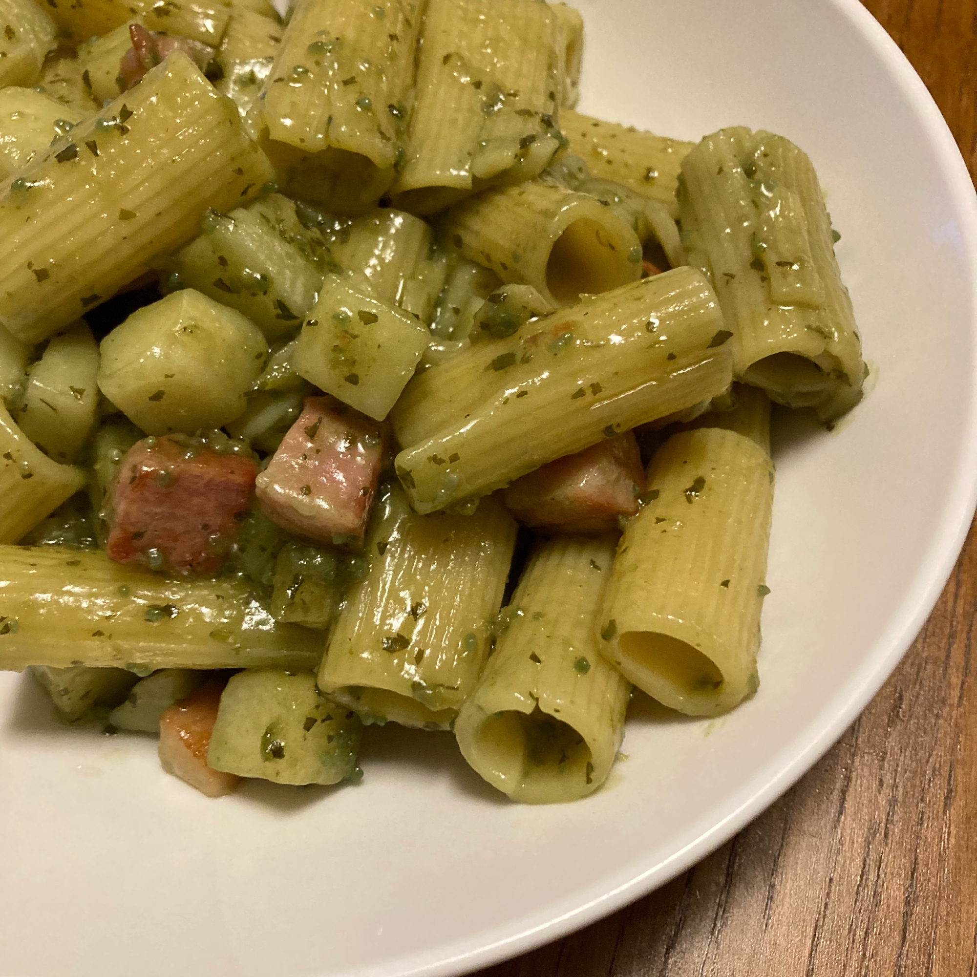 白いお皿に盛り付けられたじゃがいもとベーコンのジェノベーゼパスタ