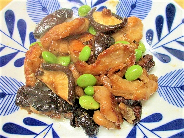 青い葉柄の皿に盛り付けられた枝豆と鶏肉の炒め物