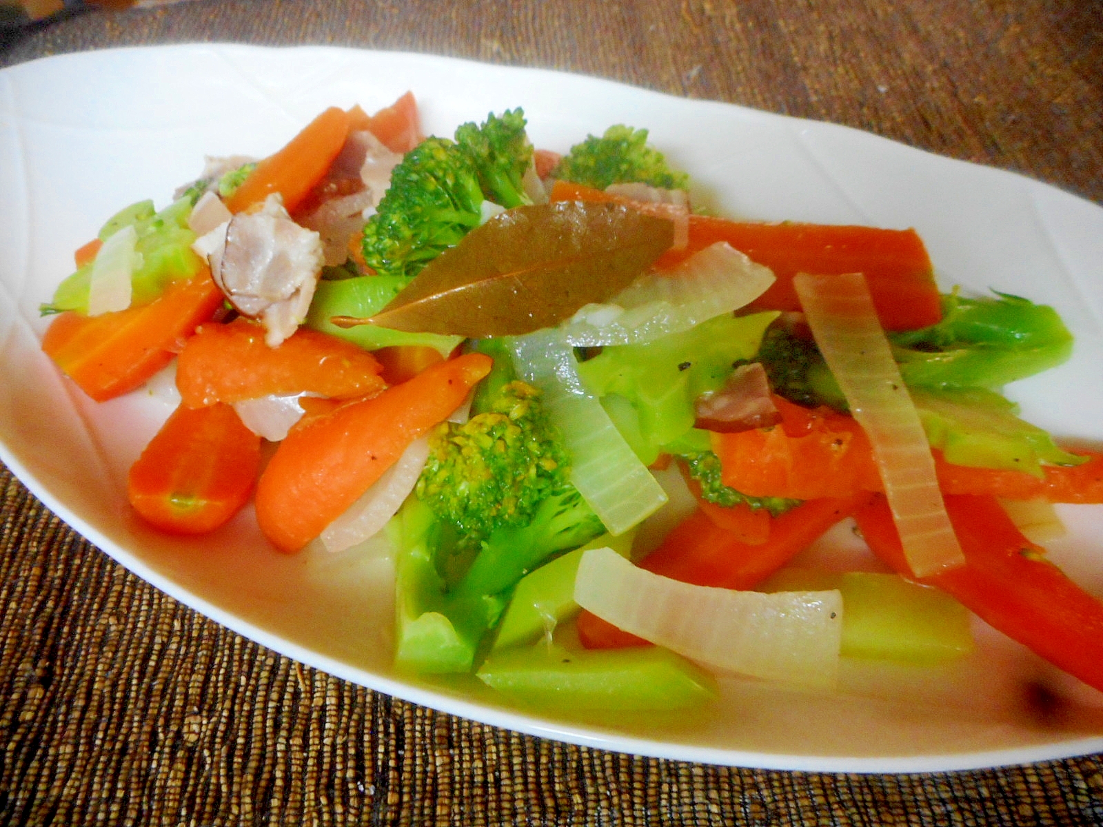 白い皿に盛り付けたブロッコリーとベーコンとにんじんの蒸し煮