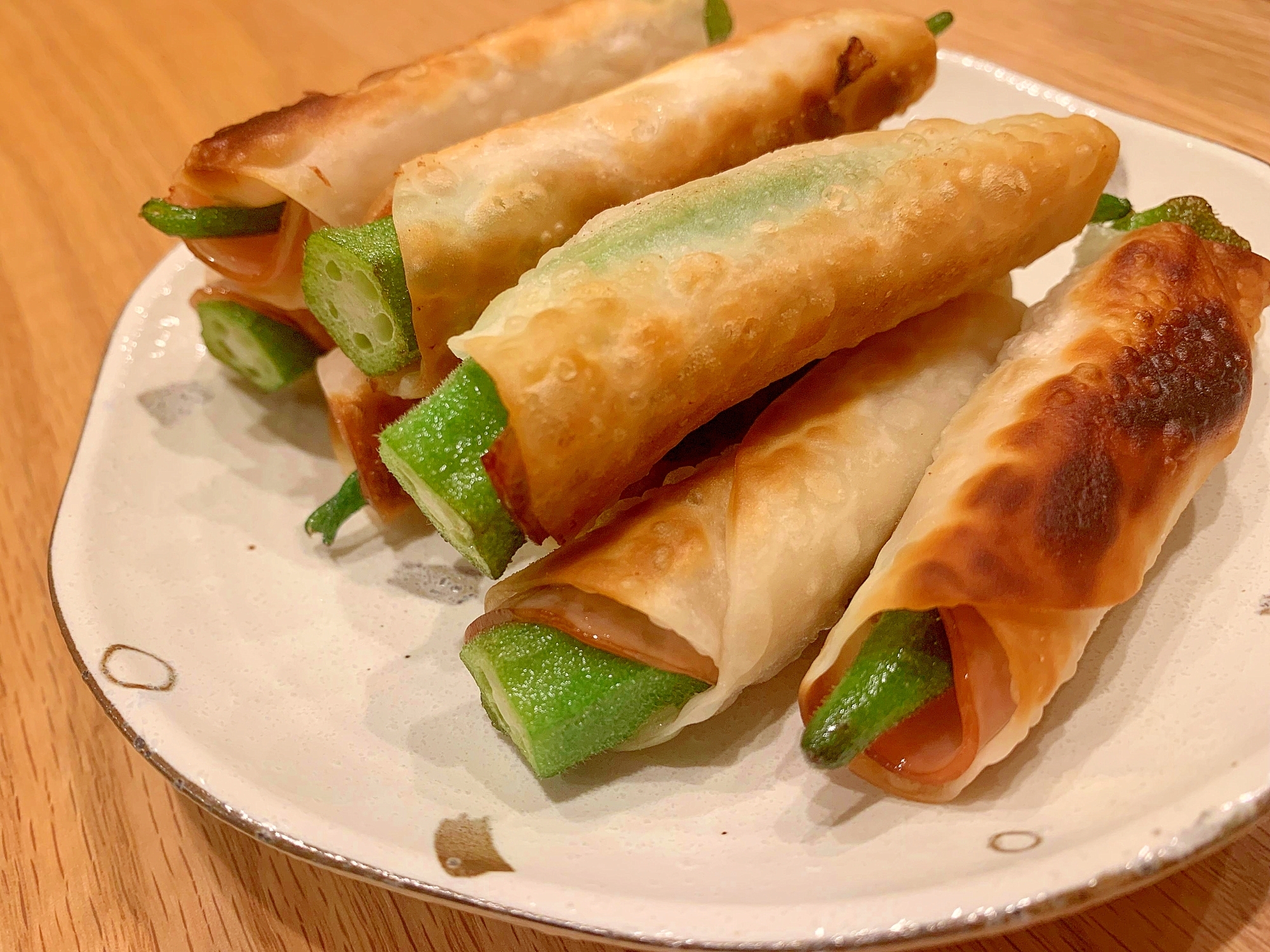 白色の皿に盛られた餃子の皮のオクラ巻き