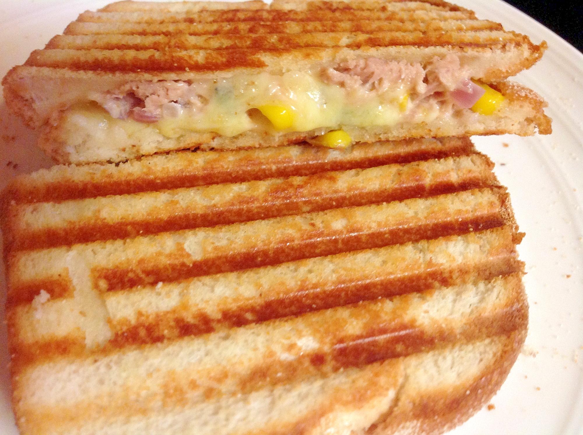 白い皿にのせたツナとコーンとチーズのホットサンド