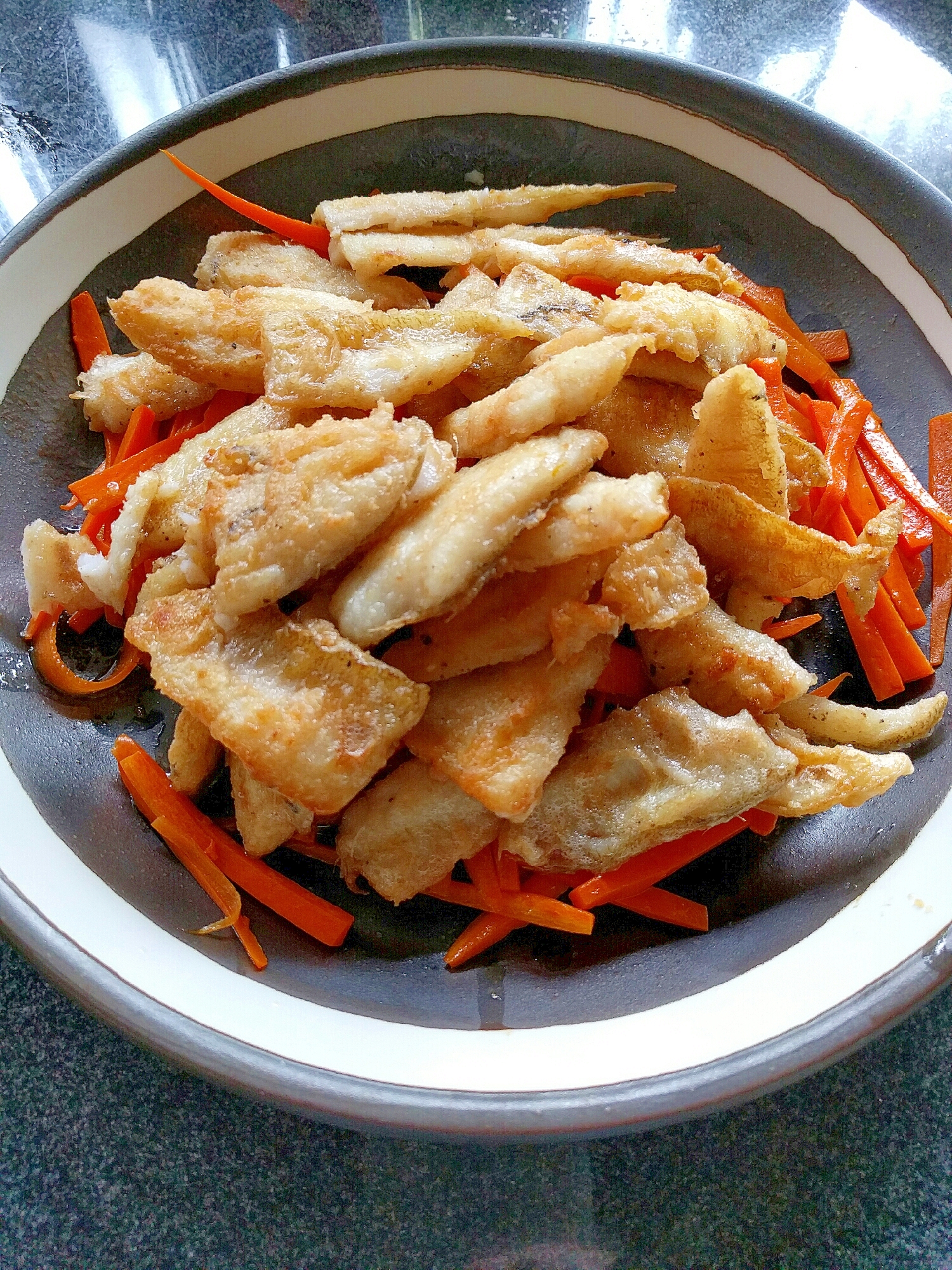 黒い皿に盛られたキスのムニエル風バター焼き