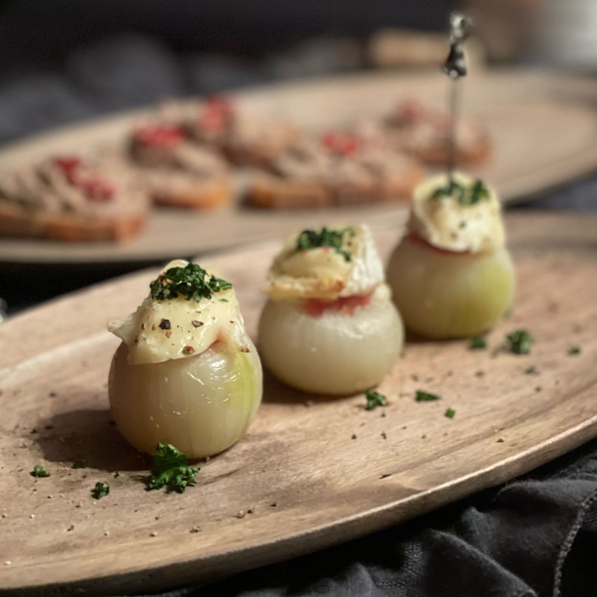 木皿に盛り付けたペコロスのカマンベールチーズ焼き