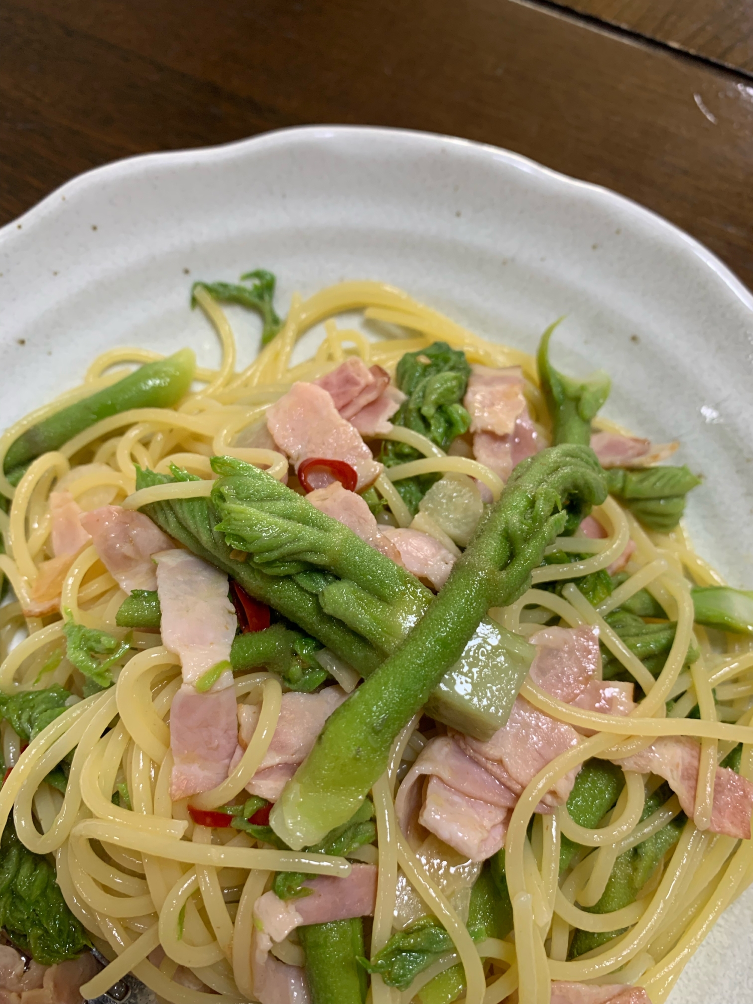 白い皿に盛られたタラの芽とベーコンのパスタ