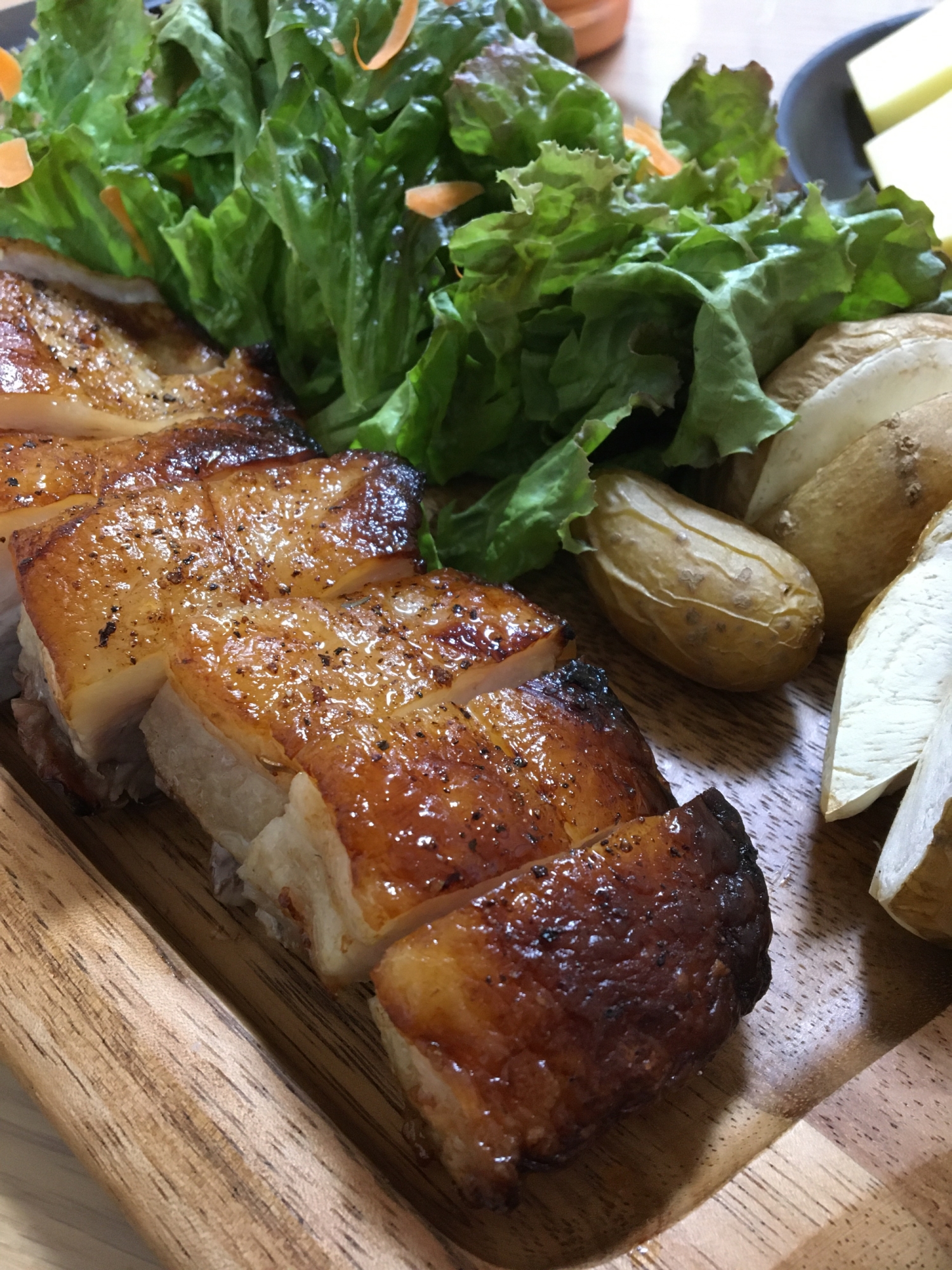 木の板に盛られた豚肩ブロック肉のオーブン焼き