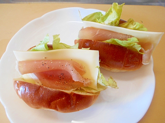 白い皿にのせた生ハム・チーズ・レタスのロールパンサンド