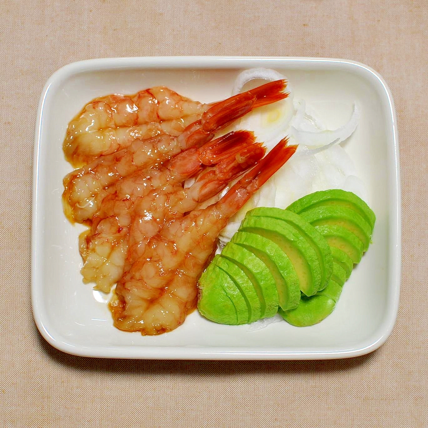 白い皿に付け合わせと一緒に盛られた、赤エビの漬け刺身