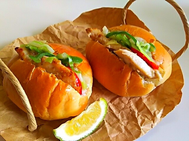 ワックスペーパーにのせたチキンソテーと温野菜ロールパンサンド