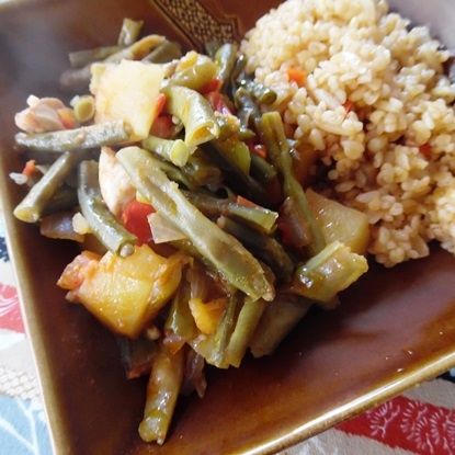 茶色の角皿に盛り付けられたささげと鶏肉のトマト煮込み