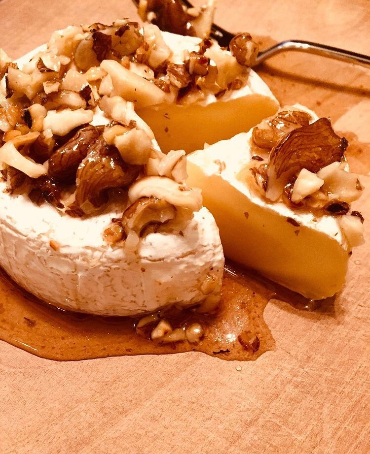木製の皿に盛り付けられたくるみとブランデーの焼きカマンベール
