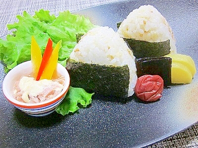 黒い皿に置かれた昆布茶と天かすとすりごまのおにぎり