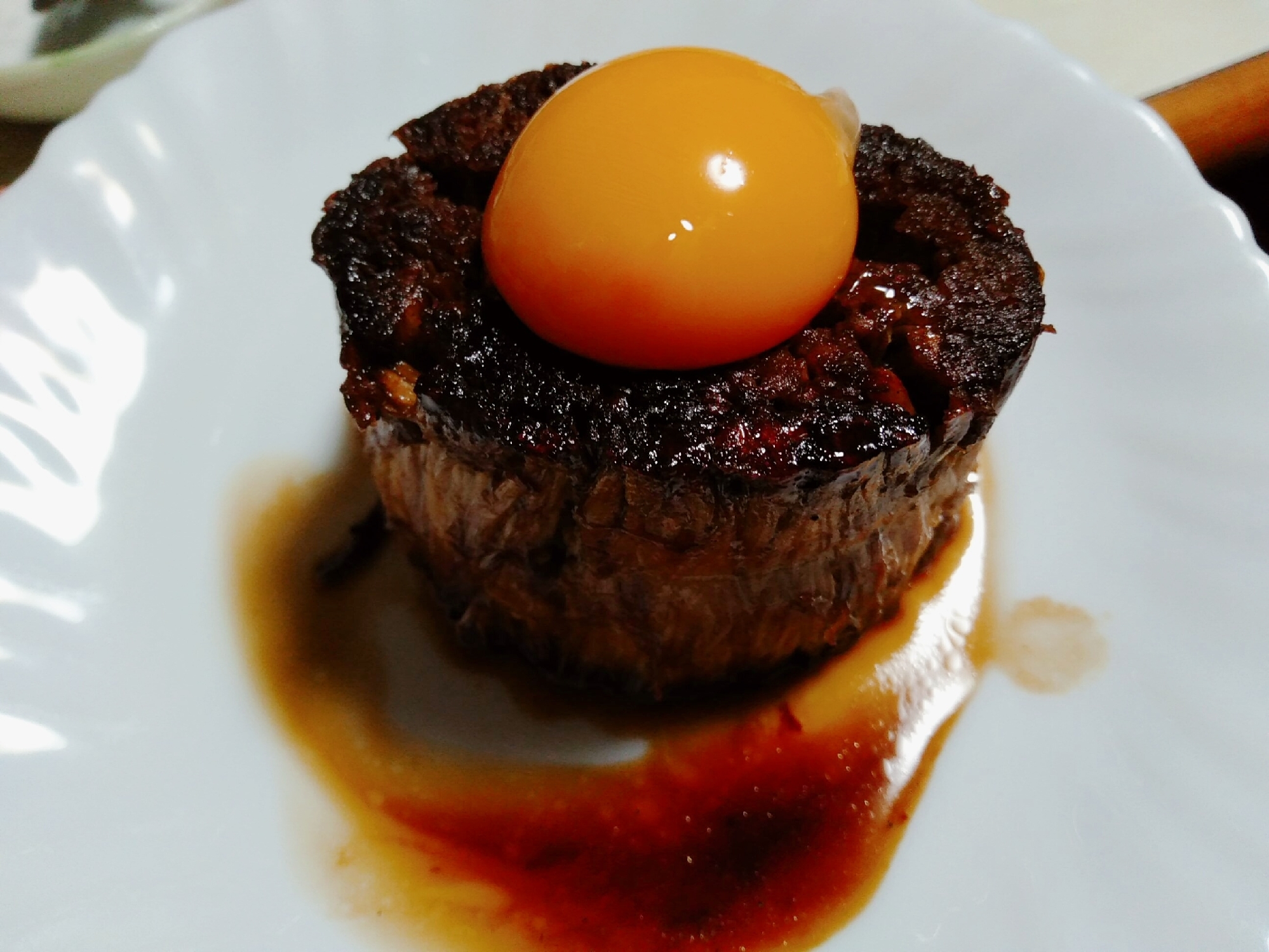 丸いお皿に盛り付けて、黄身を添えたエノキステーキ