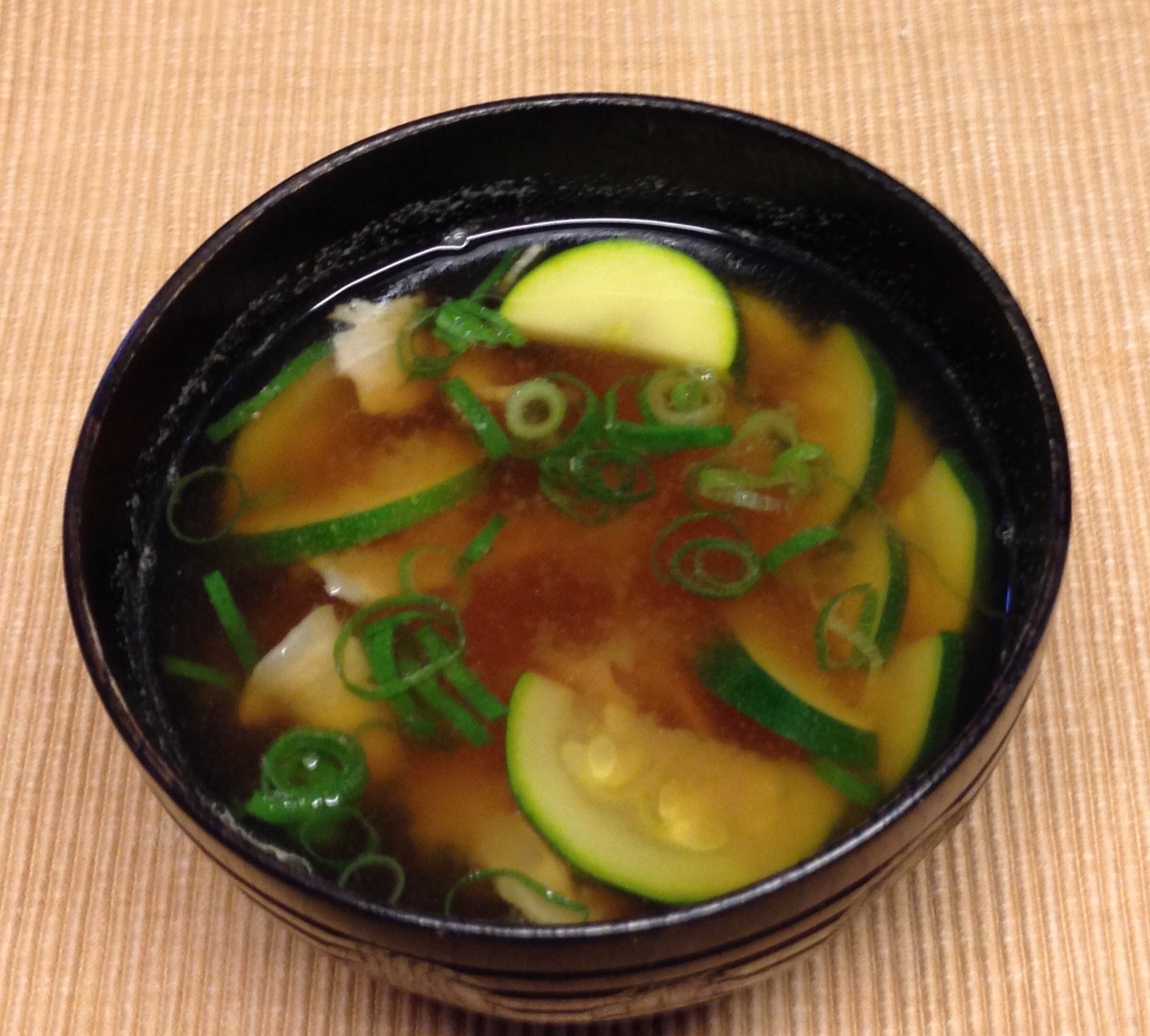 黒いお茶碗に盛られたズッキーニとベーコンのみそ汁