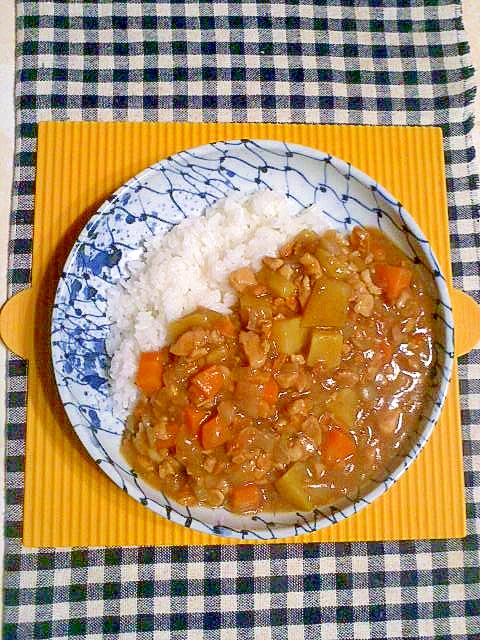 青い柄が入った白い皿に盛り付けられたピーナッツ入りカレー