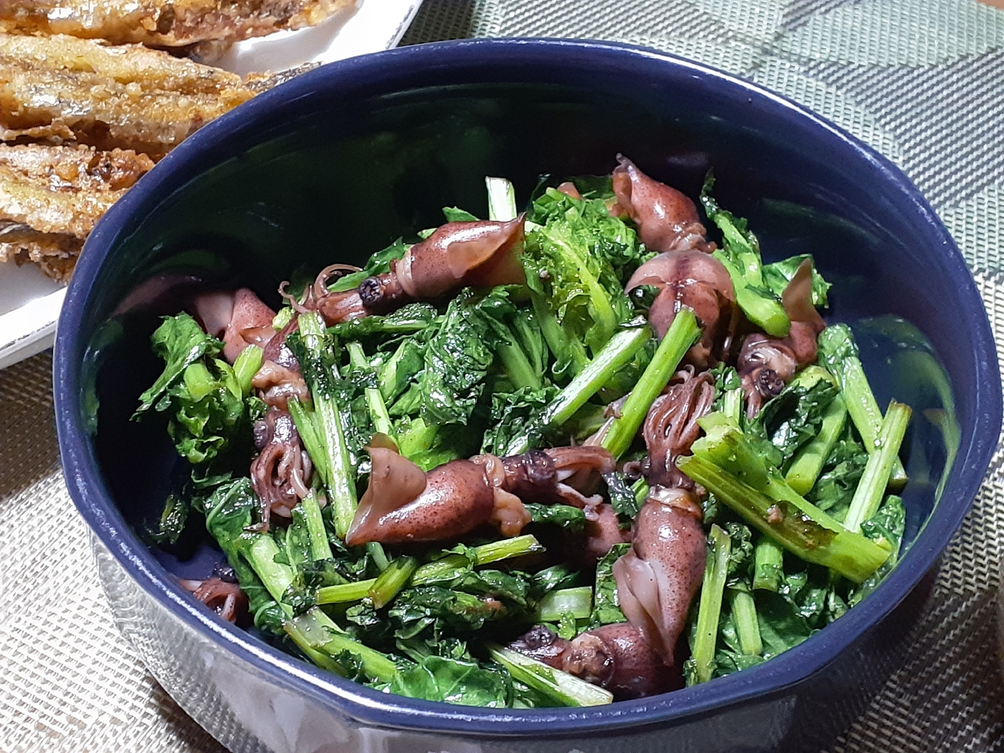 紺色の皿に盛り付けられたかき菜とホタルイカの炒め物