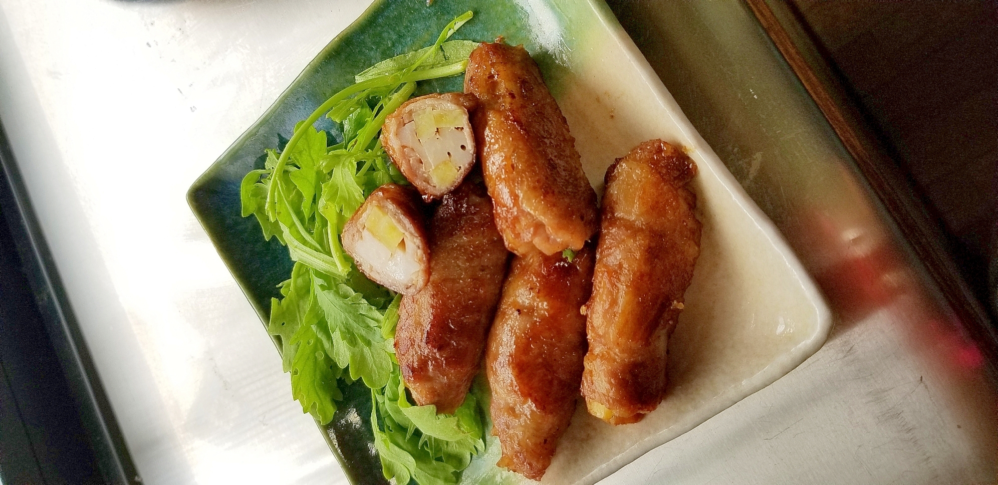 角皿に盛り付けたさつまいもとれんこんの豚肉巻き