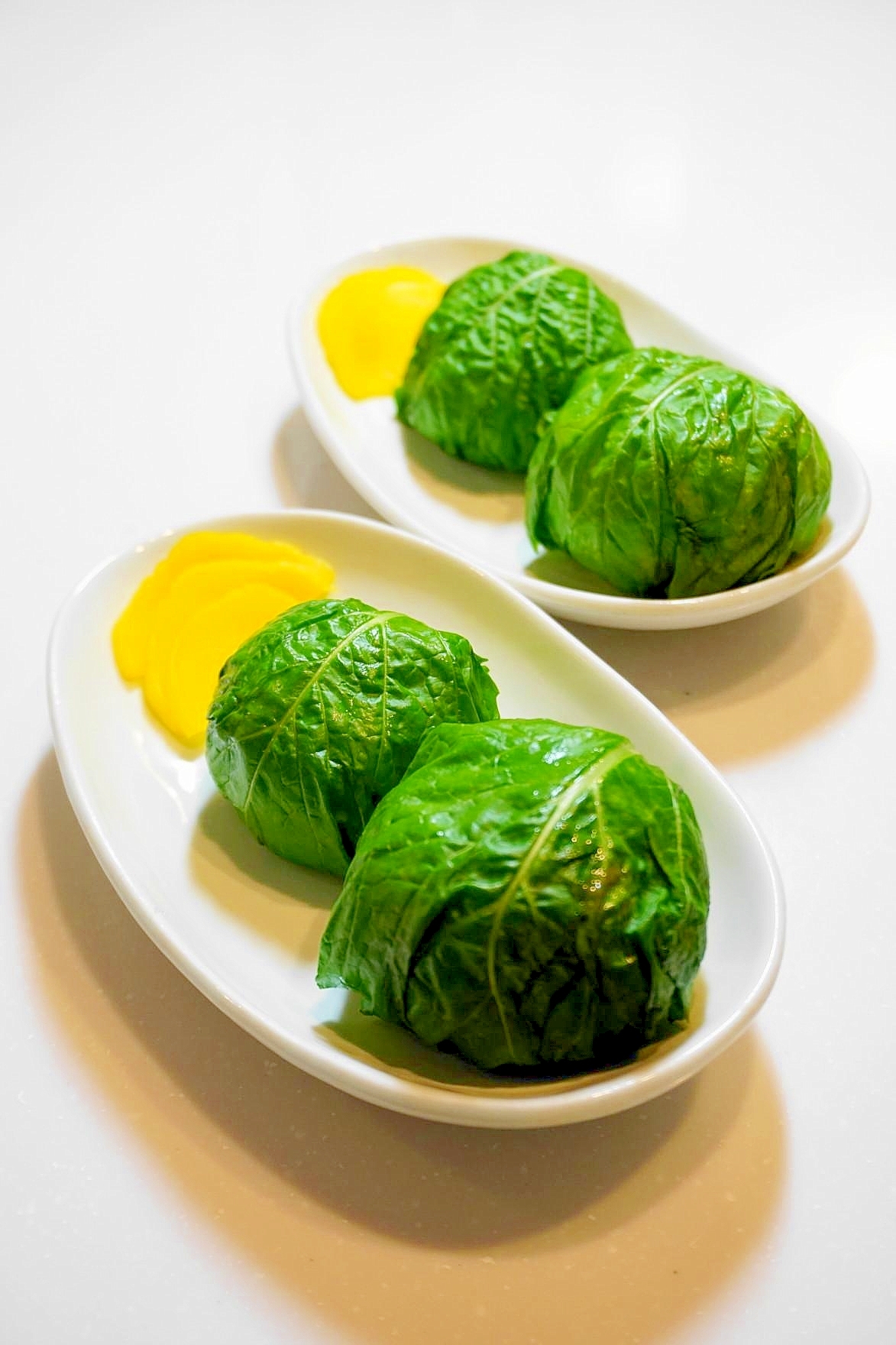 白い皿にふたつずつ置かれたかぶの葉おにぎり