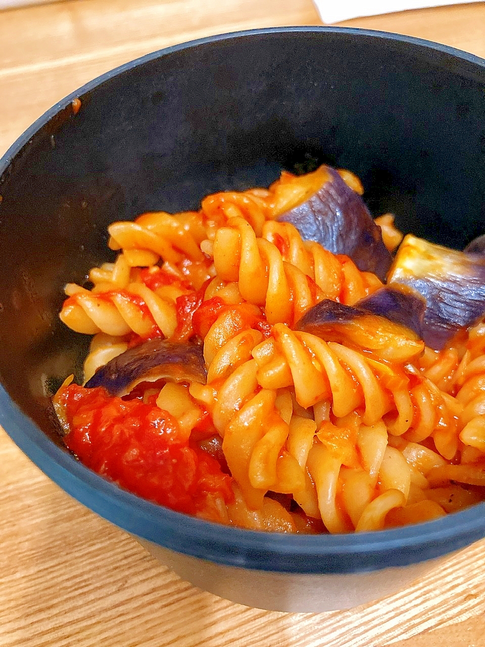 黒い器に入ったなすとトマトの煮込みパスタ