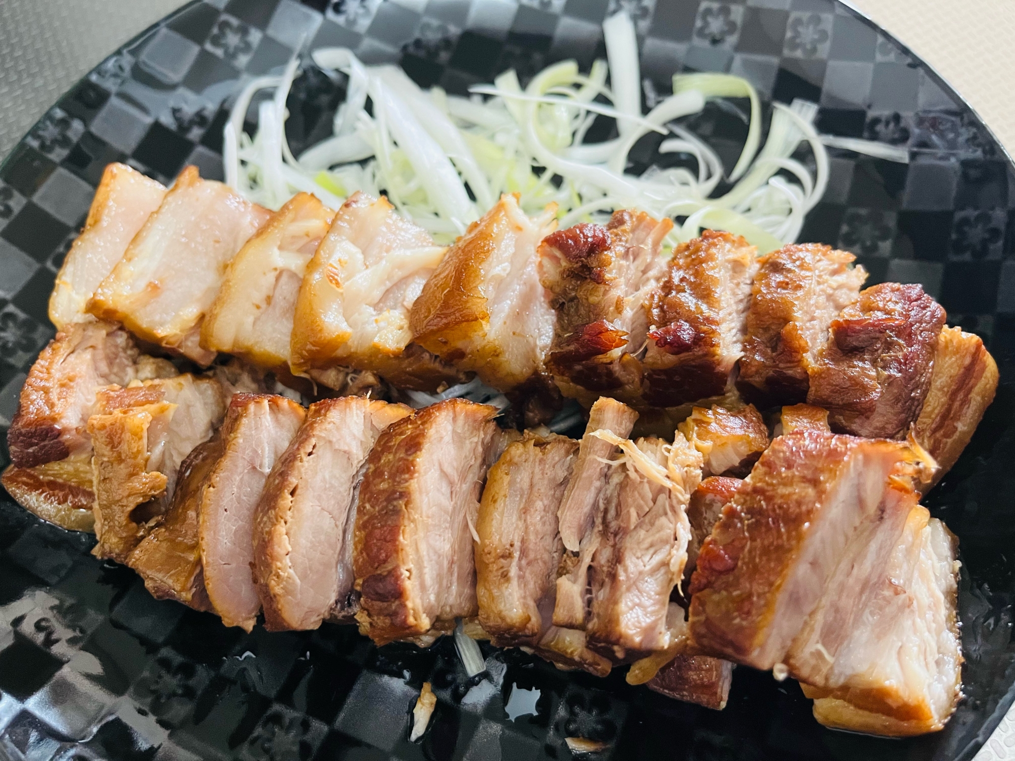 黒いお皿に盛り付けられたネギとチャーシュー