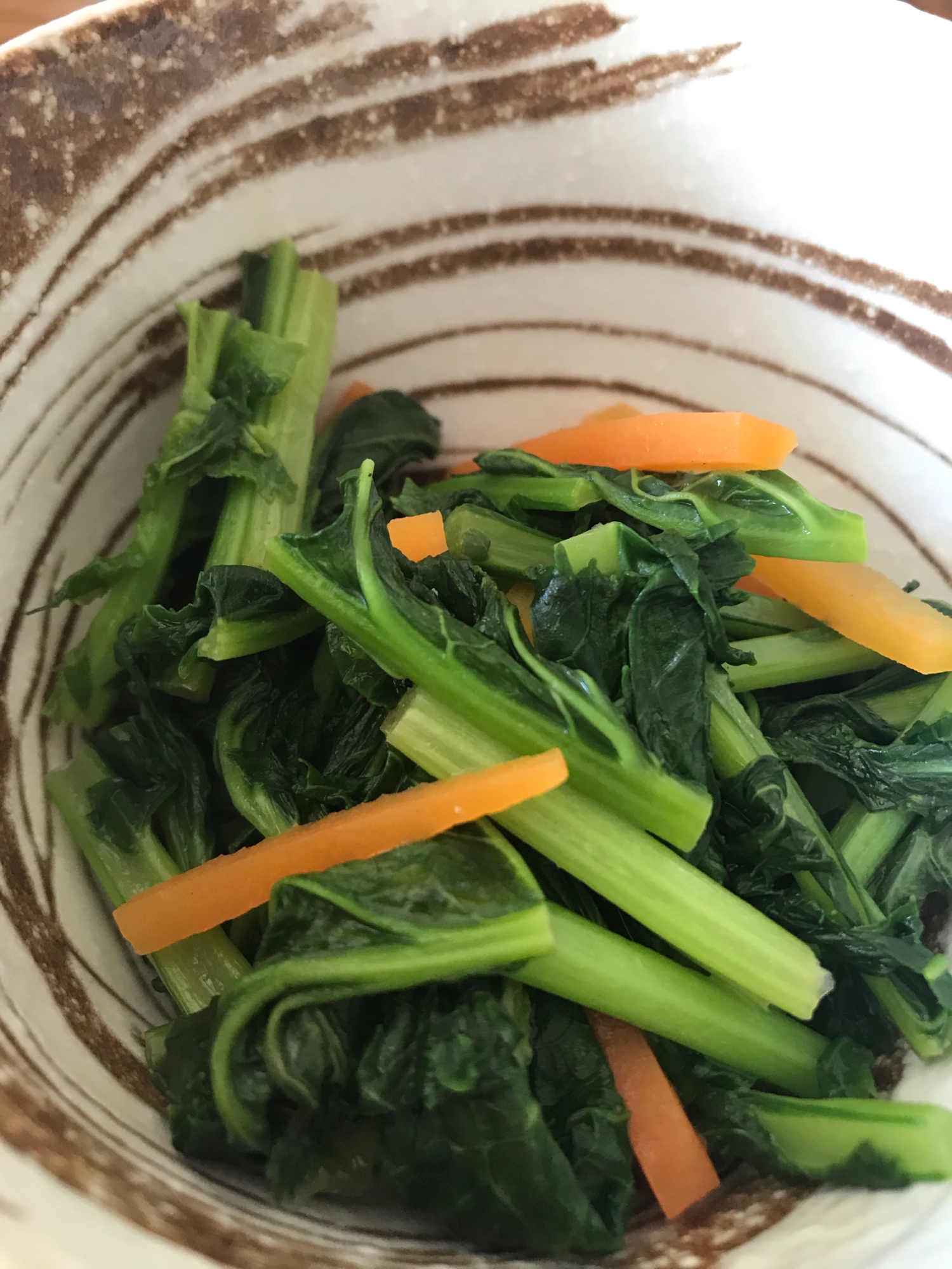 白い皿に盛り付けられたかき菜とにんじんのバターしょうゆ炒め